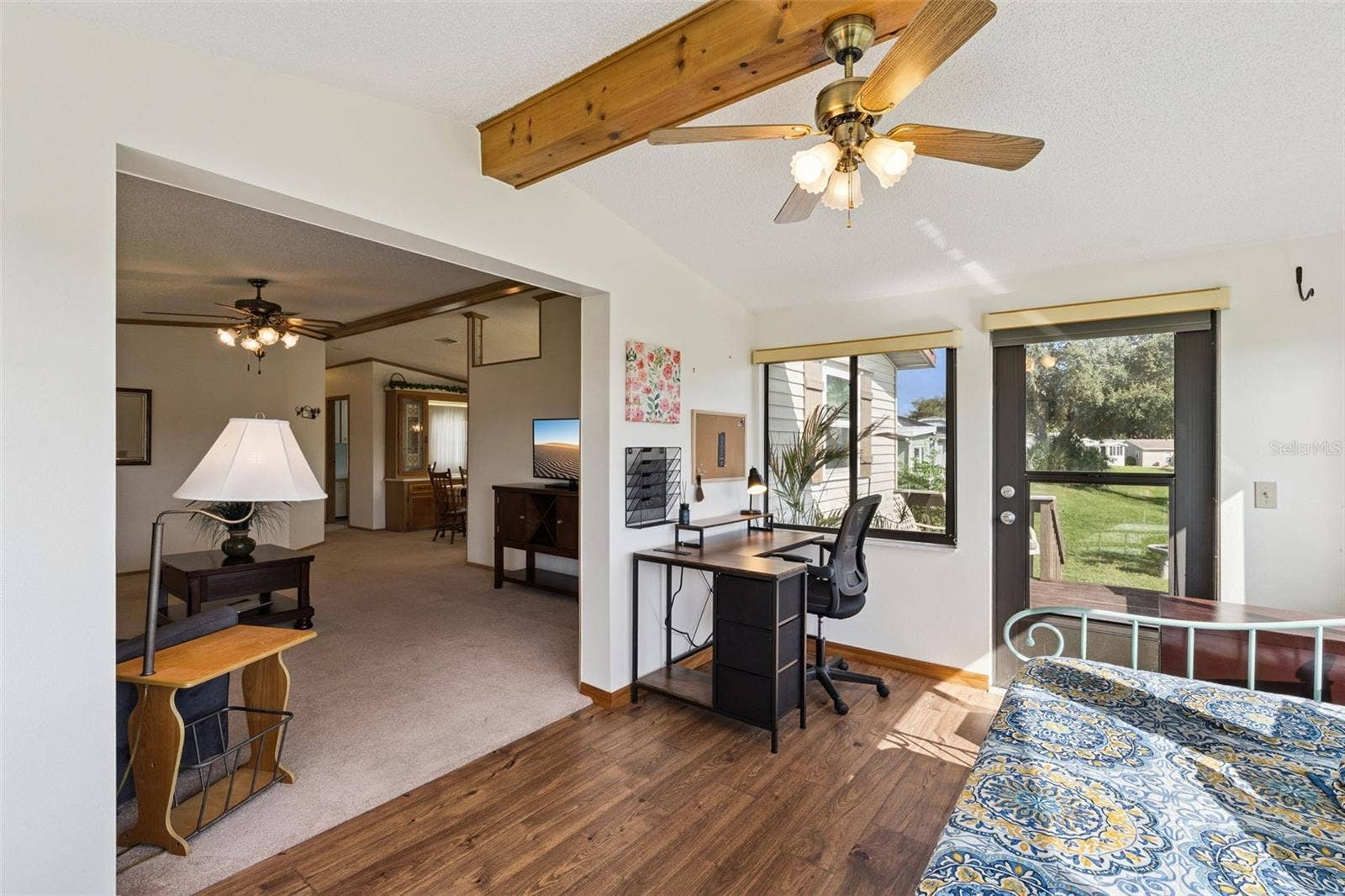 Sunroom with wood-look flooring, beamed ceiling and opening to the living room