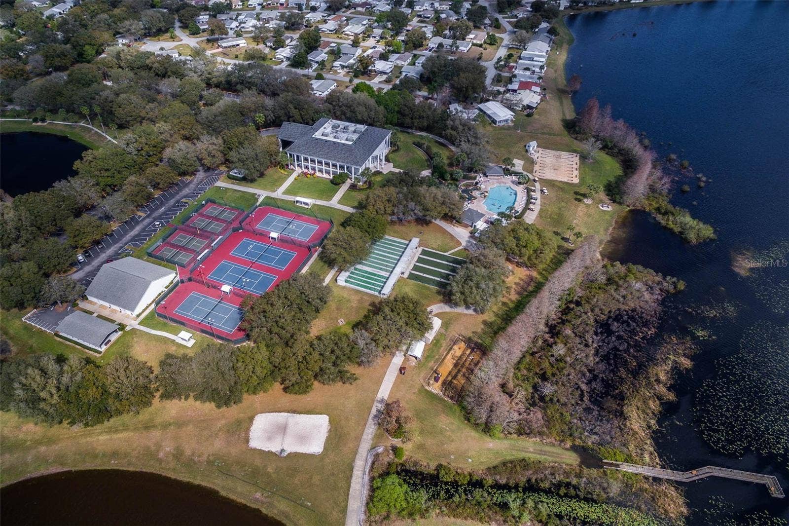 Community amenity: aerial view of the clubhouse, courts and pool along the lake