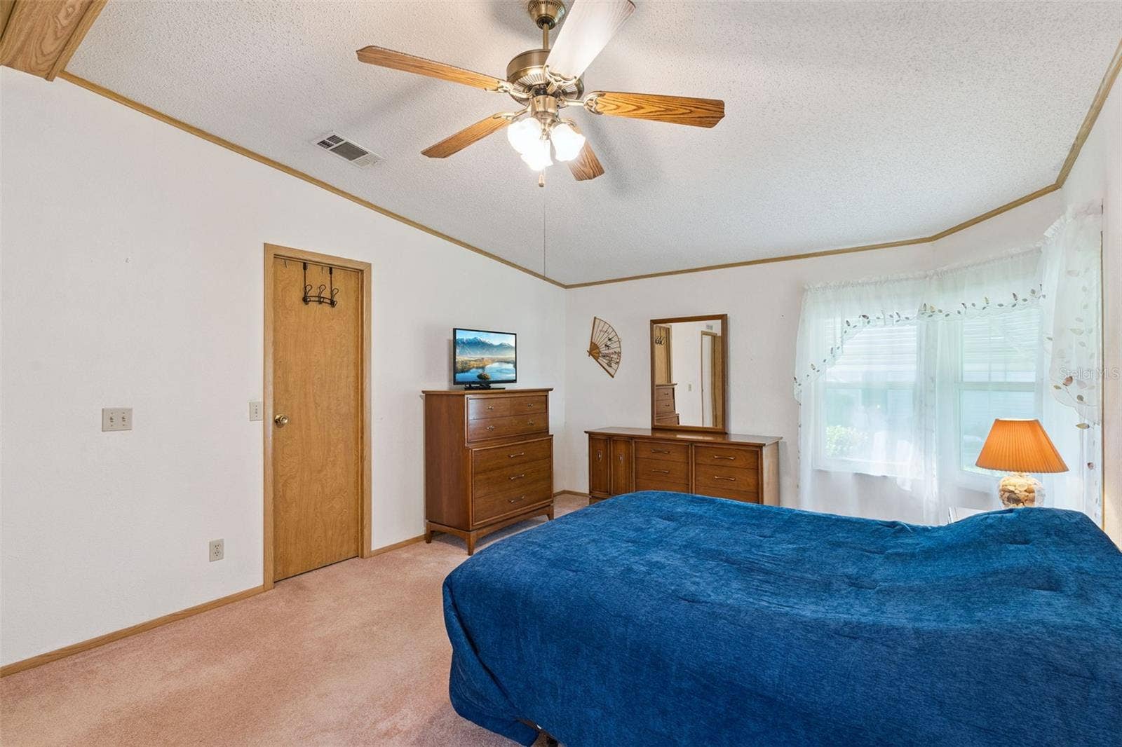 Primary bedroom with corner windows and ceiling fan