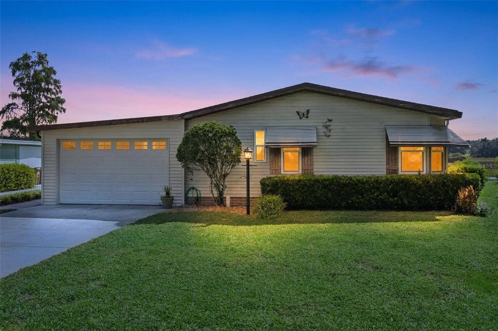 Digitally enhanced virtual twilight: front exterior with attached garage and landscaped front yard