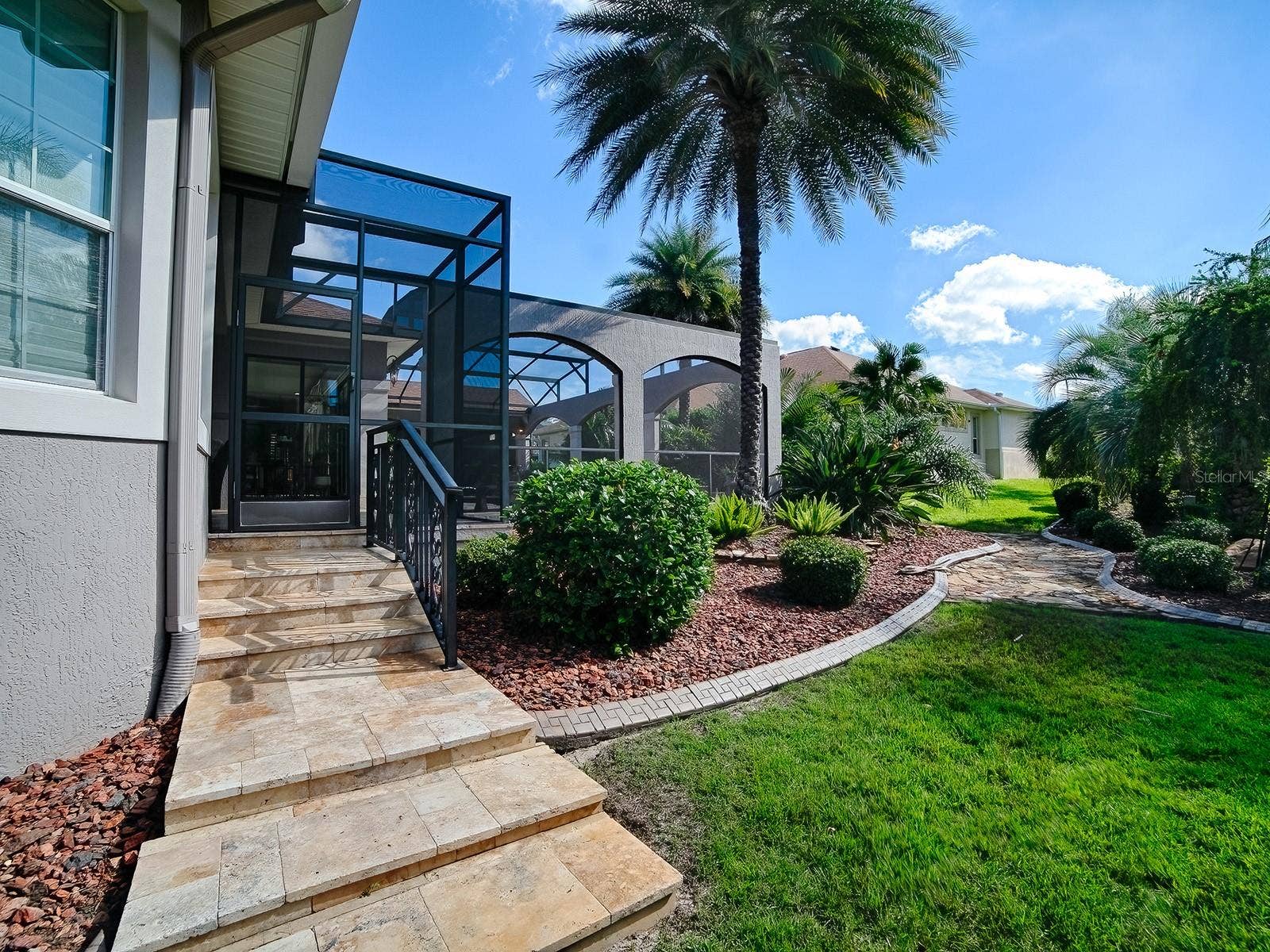 1103 MIONA SHORES DRIVE, The Villages, FL 32162 THIS IS THE RIGHT SIDE OF THE HOME WITH TRAVERTINE STEPS LEADING TO THE POOL AREA.