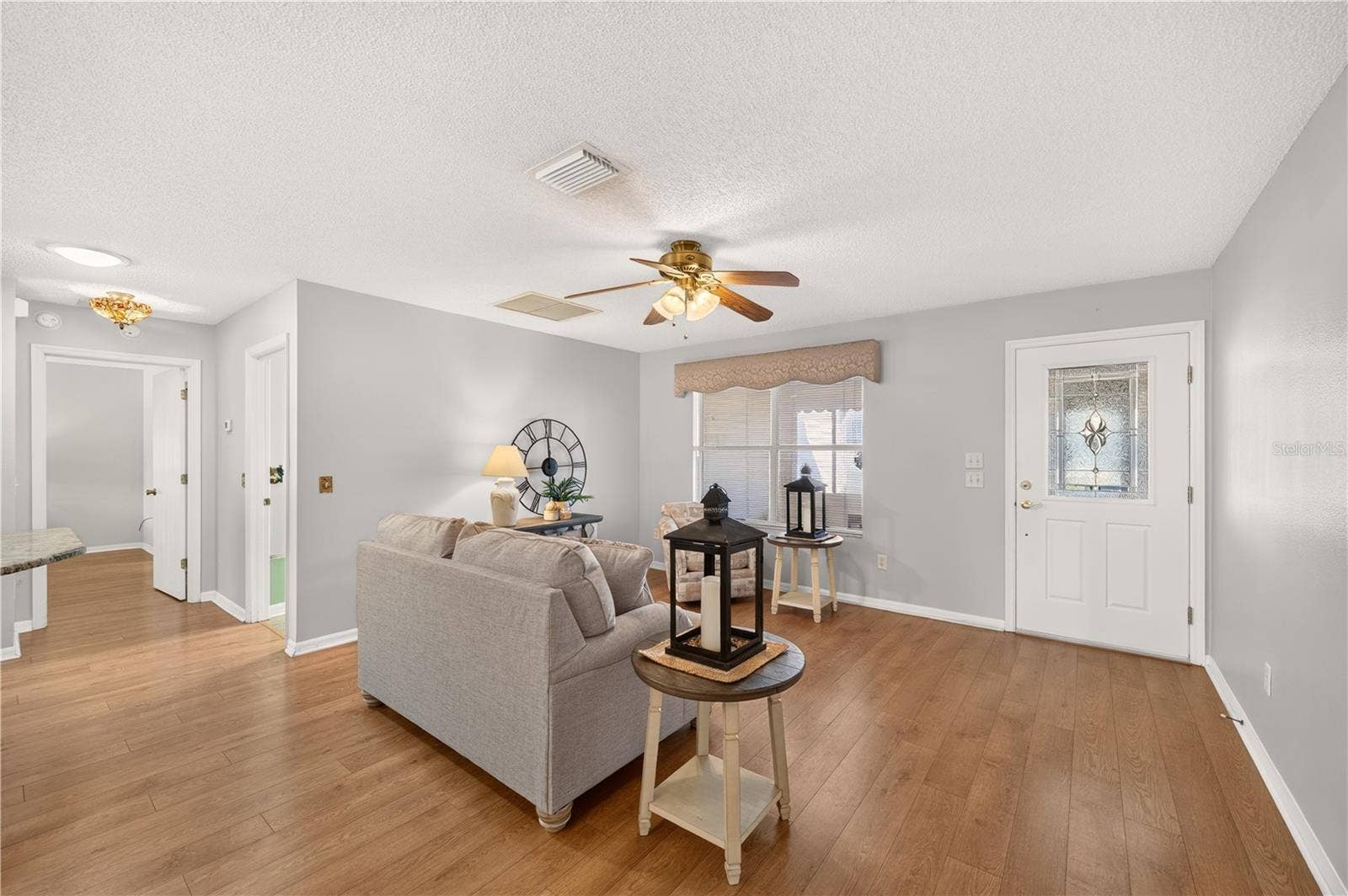 Spacious living area showcasing wood-look flooring, a decorative glass front entry door, natural light, and an open floor plan that creates an easy flow throughout the home.
