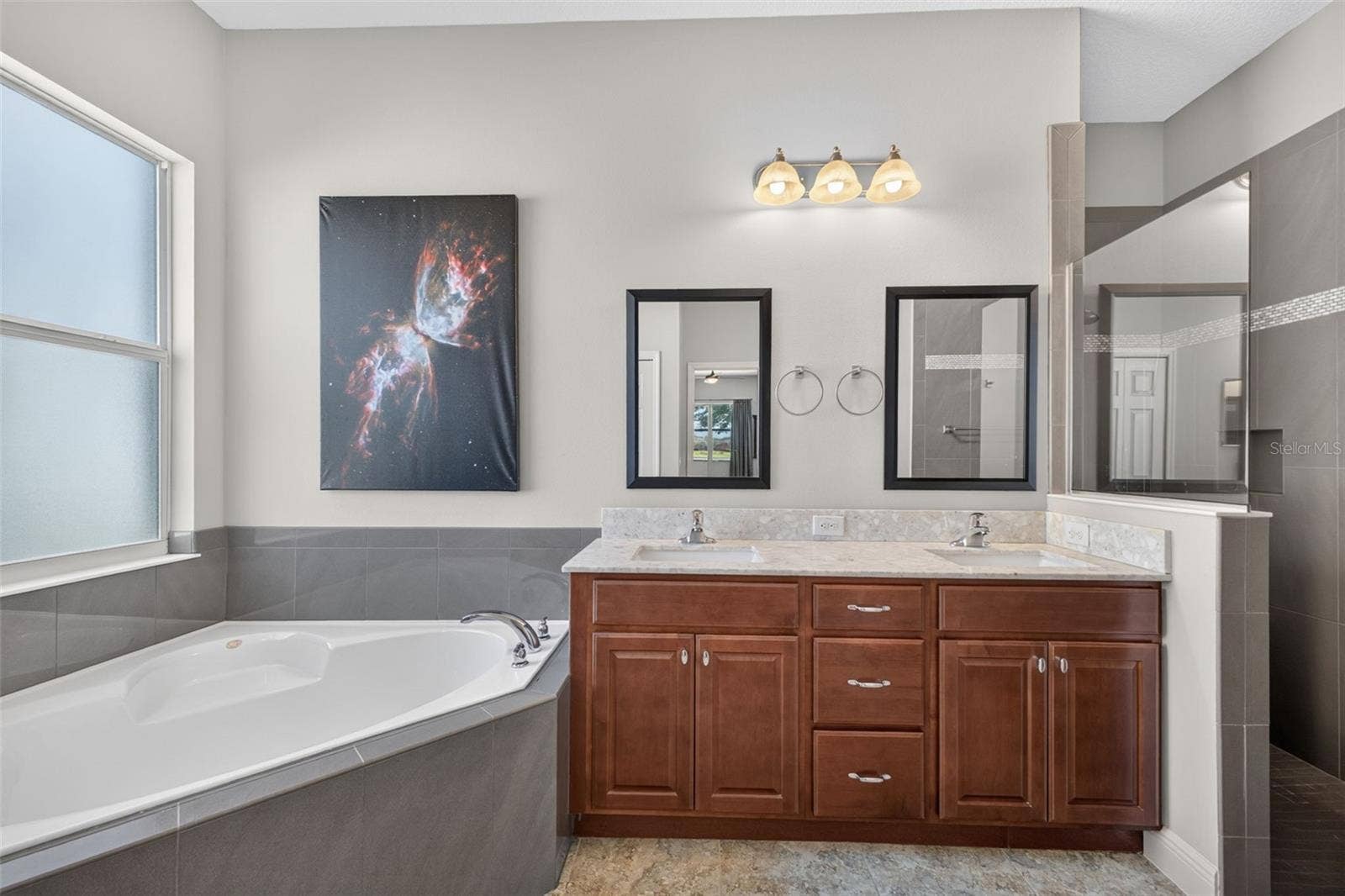 2444 PAWTUCKET PASS, Mount Dora, FL 32757 Dual vanity sinks and generous wood cabinetry provide abundant storage and counter space for effortless morning routines.