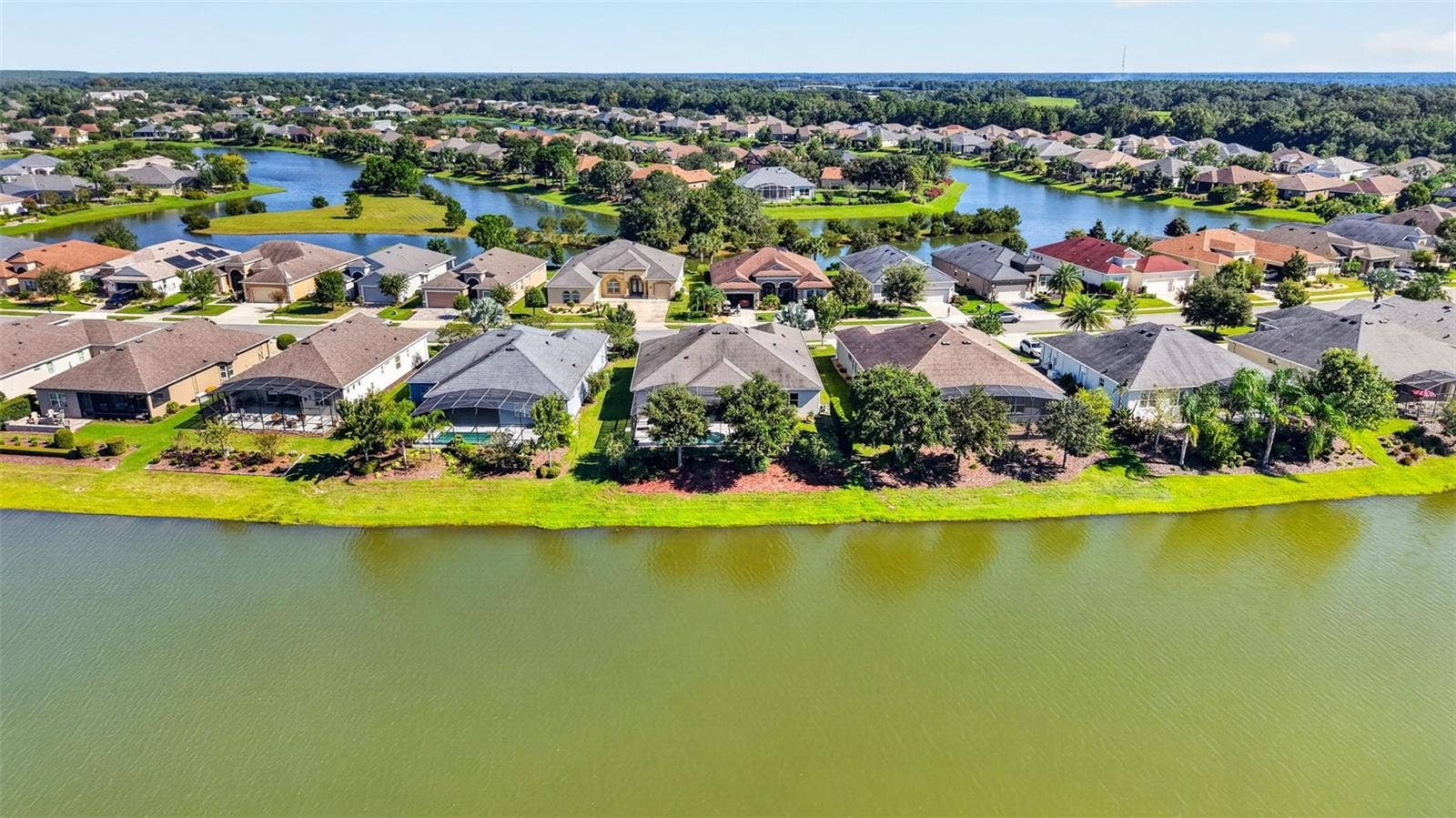 2444 PAWTUCKET PASS, Mount Dora, FL 32757 An aerial drone perspective captures the rear elevation of the home, perfectly positioned along the lake.