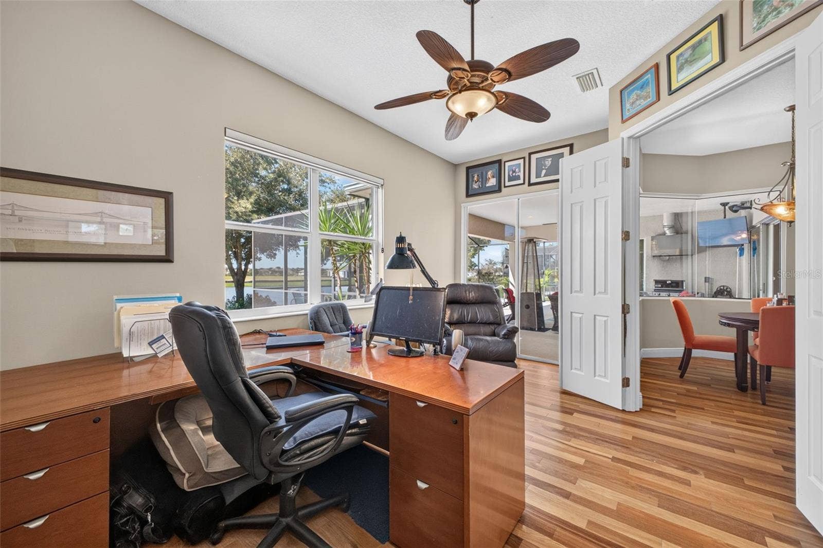 2444 PAWTUCKET PASS, Mount Dora, FL 32757 Framed by serene lake views, this dedicated home office features sliding glass doors that step directly out onto the lanai for an inspiring indoor-outdoor workspace.