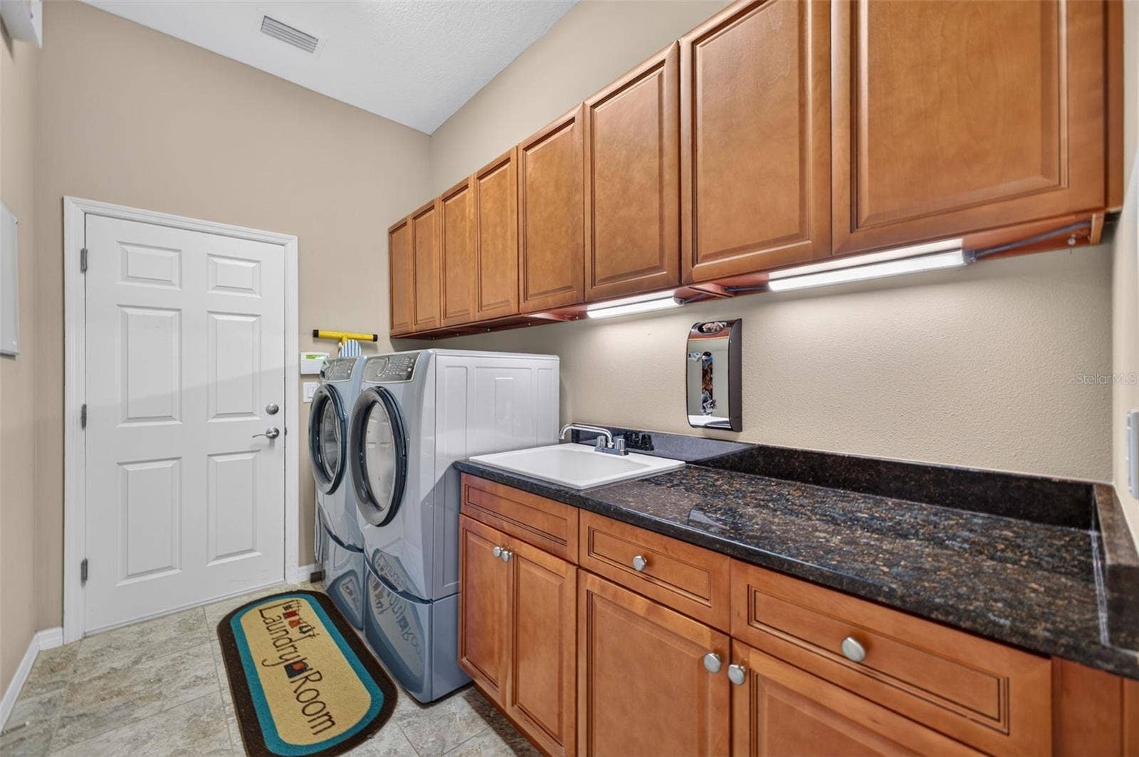 2444 PAWTUCKET PASS, Mount Dora, FL 32757 Equipped with rich granite counters, a built-in utility sink, and abundant cabinet storage, this interior laundry room doubles as a convenient drop zone with direct garage entry.