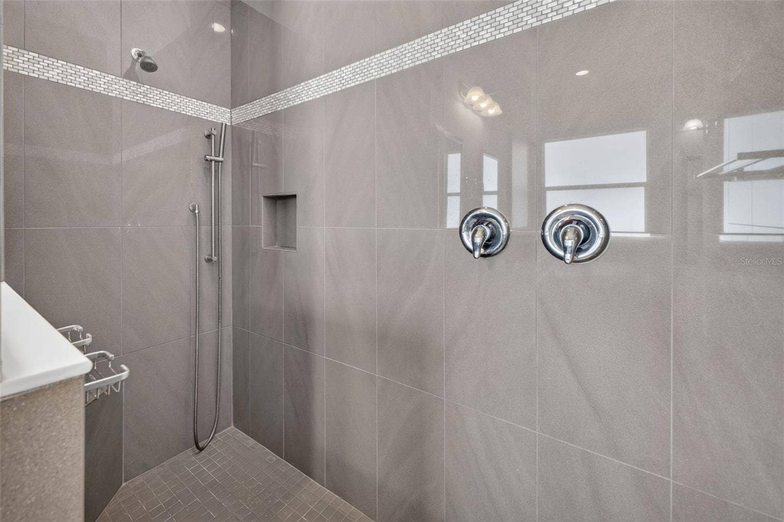 2444 PAWTUCKET PASS, Mount Dora, FL 32757 Floor-to-ceiling custom tilework and an accent detail wall give the walk-in shower a striking, spa-like feel.