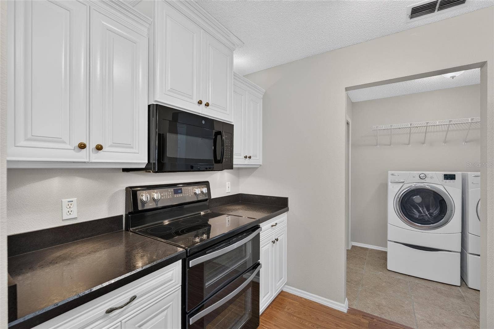 KITCHEN -View of a DOUBLE OVEN and OTC MICROWAVE HOOD which are located on the south wall of the kitchen. INDOOR LAUNDRY is visible on R.