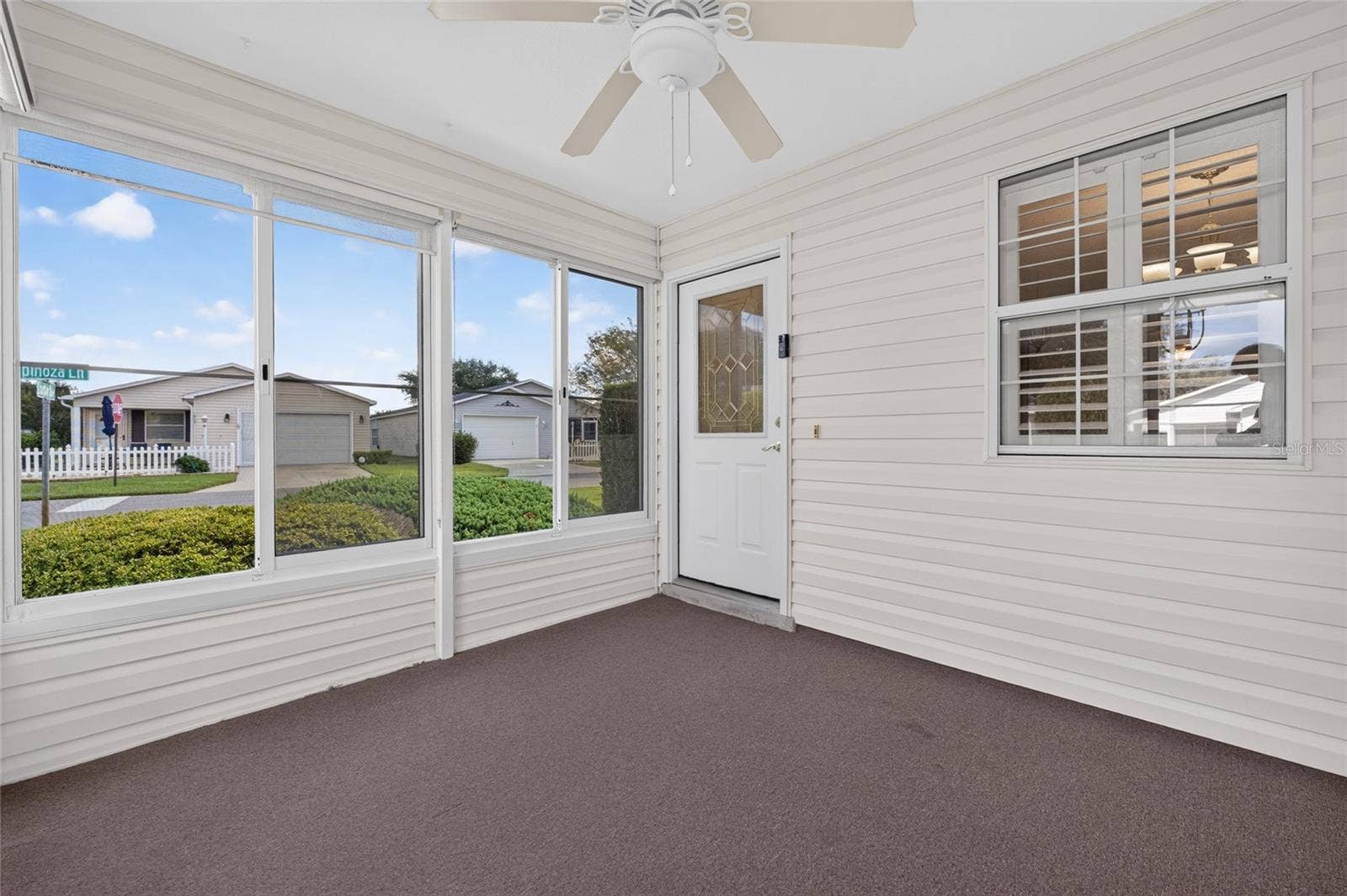 ENCLOSED LANAI / FRONT ENTRY - A half-lite front door with a DECORATIVE LEADED-GLASS INSERT design of geometric shpes, privacy glass & bright brass caming welcomes you into this lovely villa.