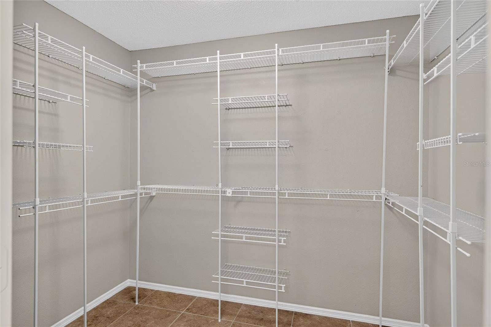 WALK-IN CLOSET - Shelving and hanging rails line multiple walls for generous storage space.