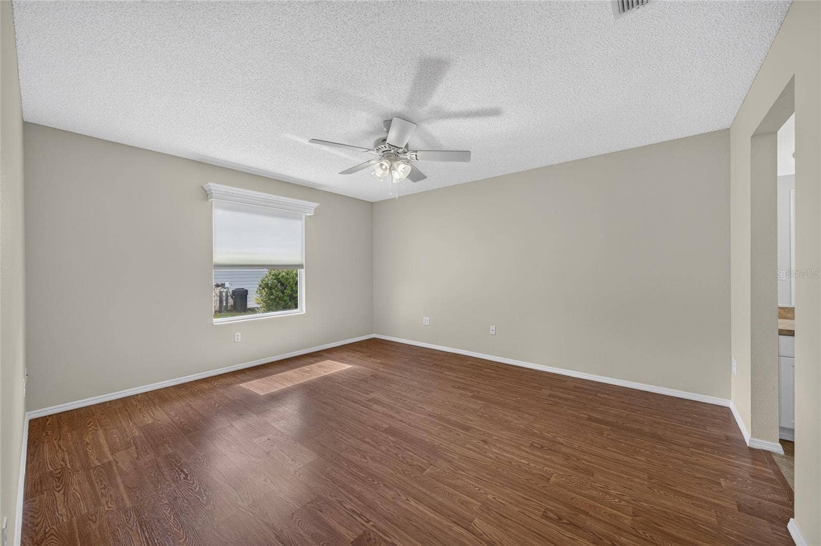 PRIMARY BEDROOM view from the doorway - Note white wooden window cornice and ceiling fan with light.