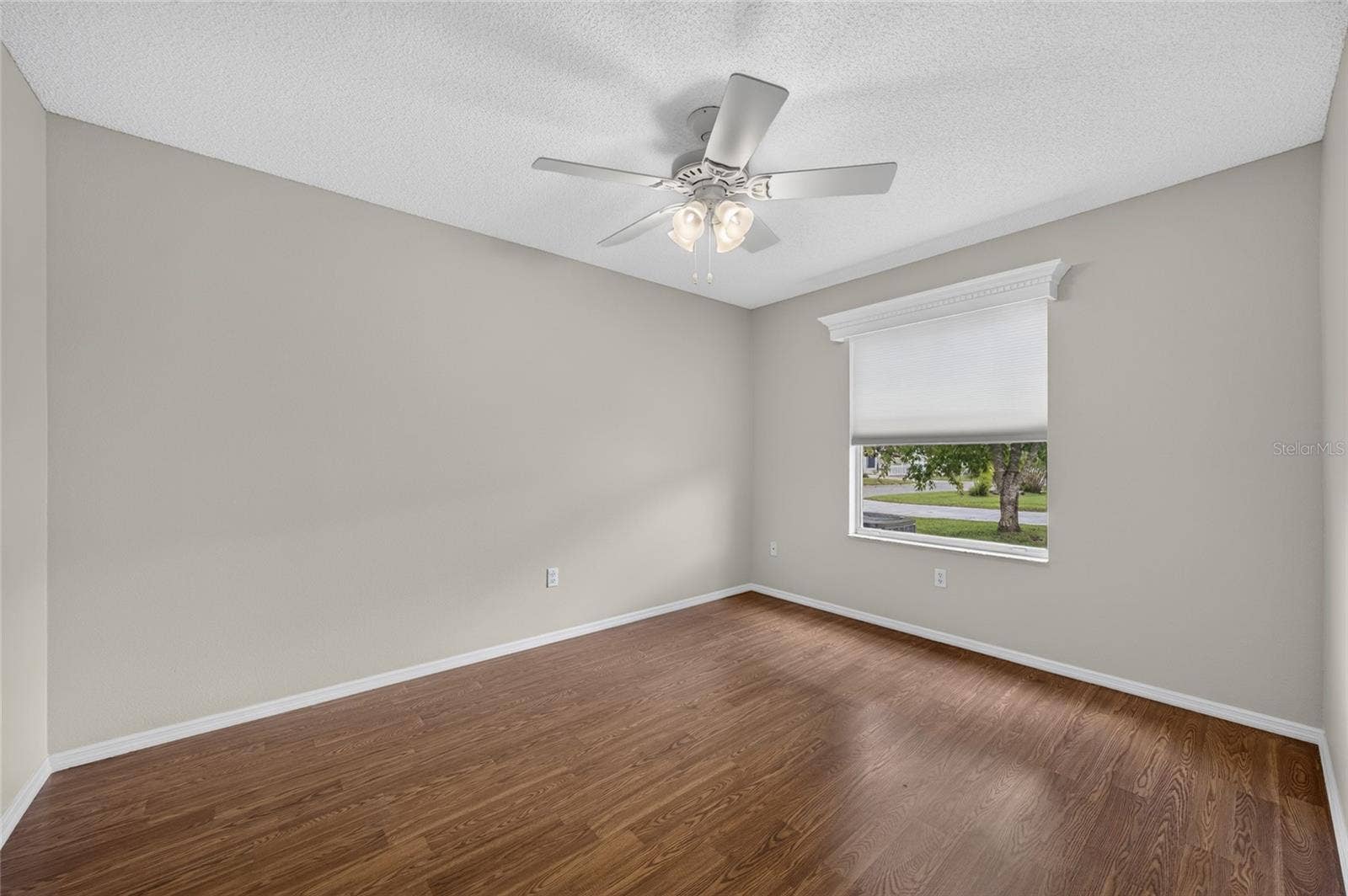 View of BEDROOM #2 from doorway - Shows large window with white wooden window cornice and ceiling fan with light.