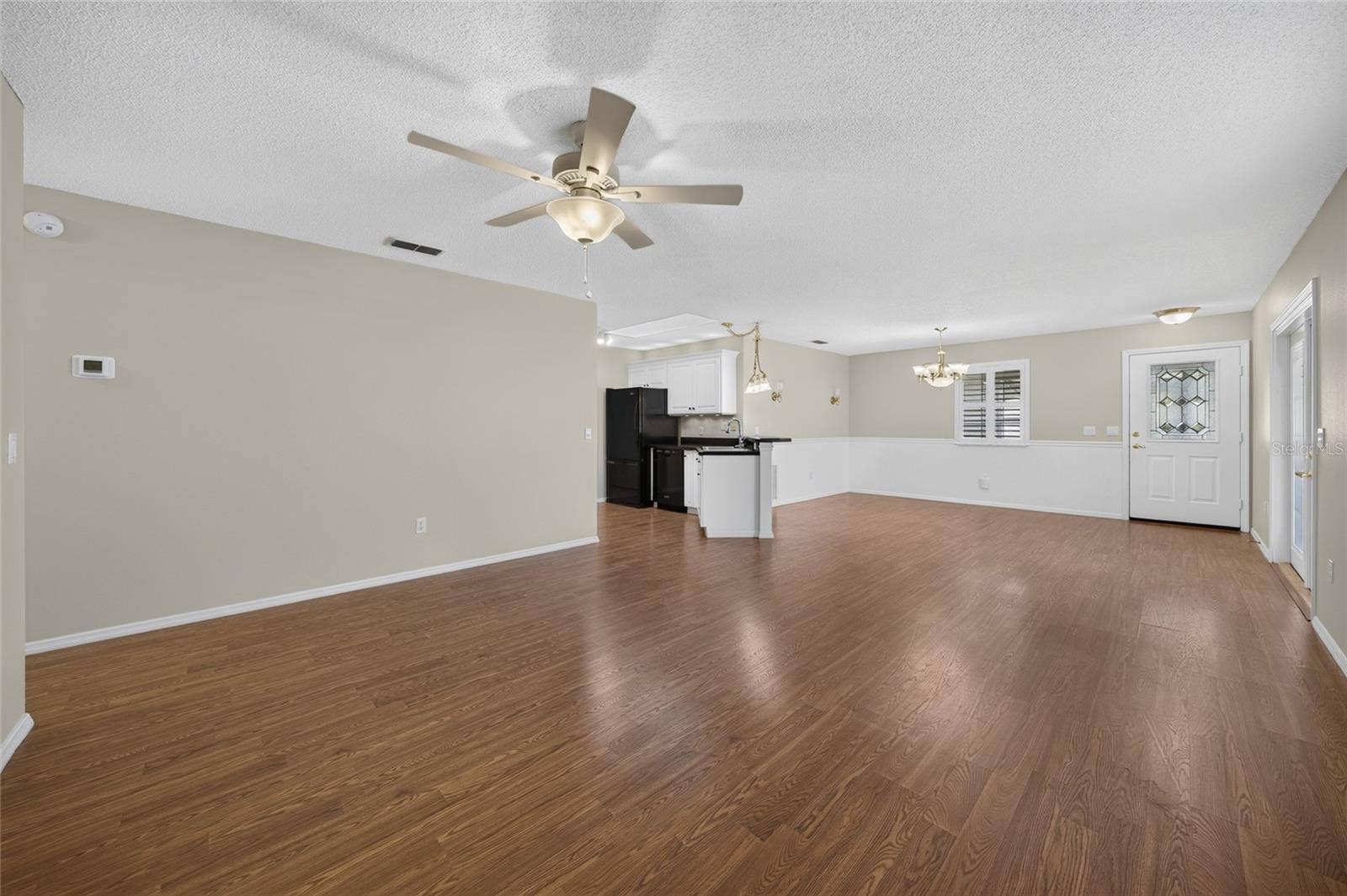 View from back of LIVING ROOM - Shows an alternate view of the main living area - LIVING ROOM (front), KITCHEN (center L), and DINING ROOM (across back)
