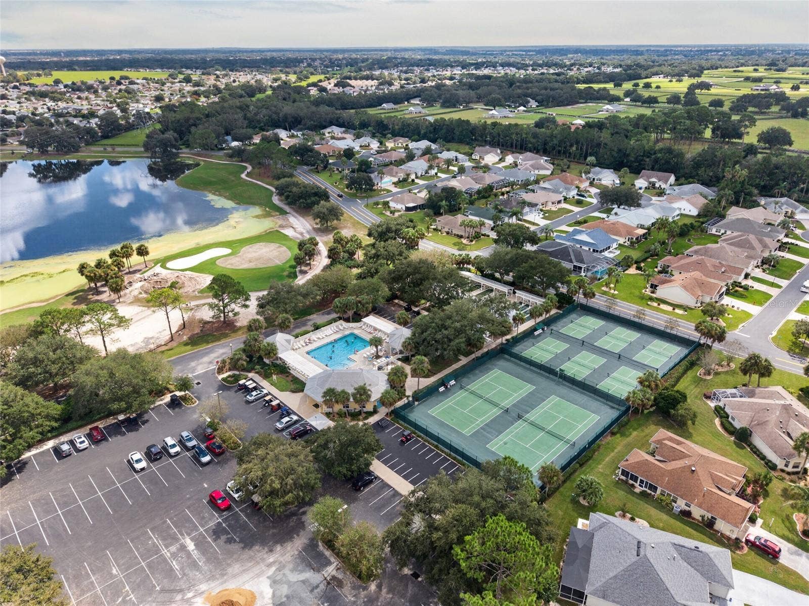 EL SANTIAGO RECREATION area / AERIAL - Overview of the community recreation grounds, with neighborhood homes and golf-course greens in the background.