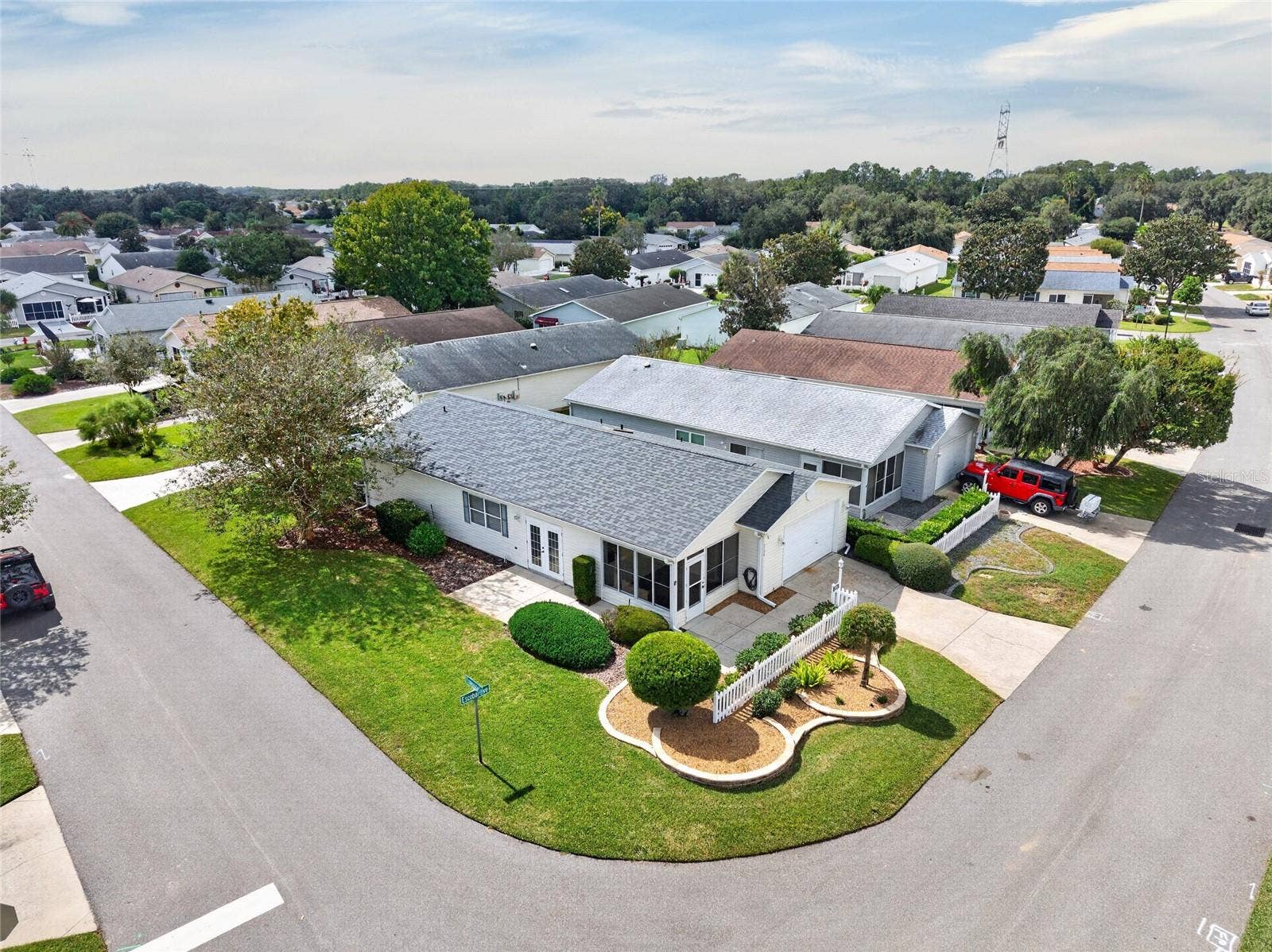 AERIAL VIEW / CORNER LOT - Low aerial view of the villa's CORNER LOT, driveway, front landscaping and adjoining streets.