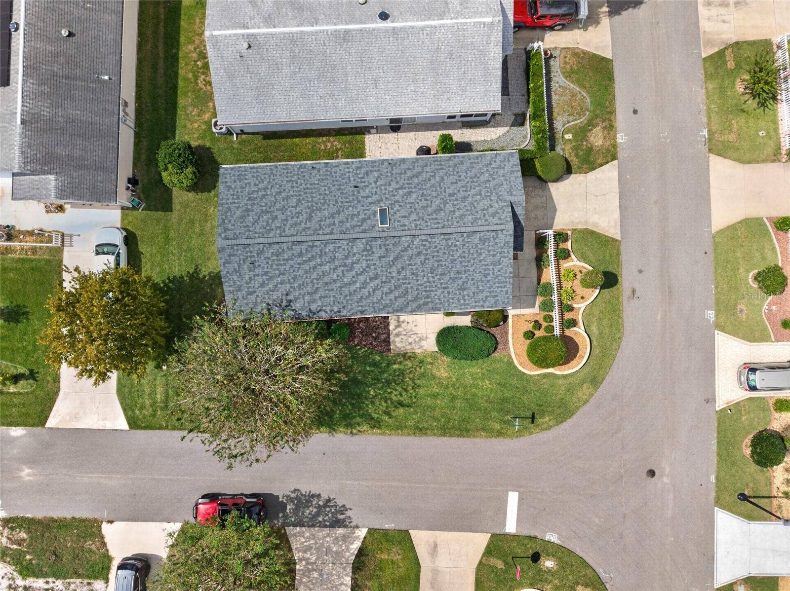 OVERHEAD AERIAL - Top-down view of the ARCH SHINGLE ROOF (2025) and the villa's footprint on a corner lot between the adjoining streets.