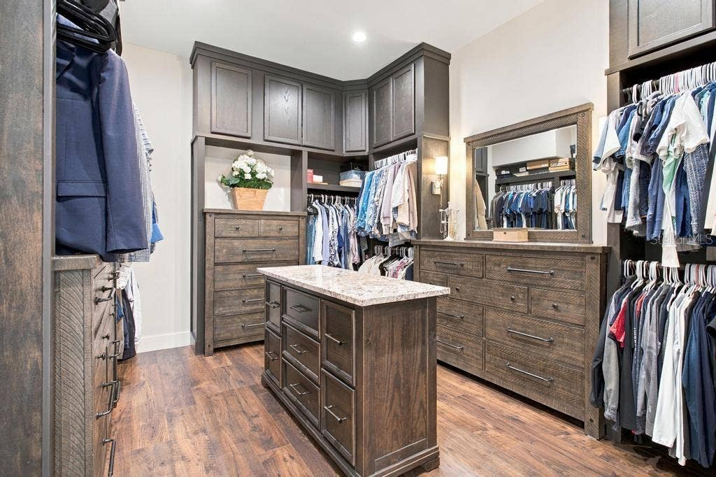 Spacious custom closet with island and built-in furniture