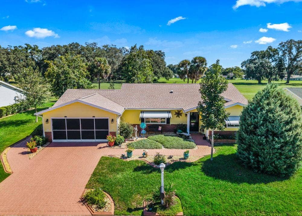 17909 SE 99TH AVENUE, Summerfield, FL 34491 Welcome to this charming 2-bedroom, 2-bathroom home featuring cheerful yellow siding, a brick-paver driveway and walkway, screened garage, and a covered front porch. Mature trees, manicured landscaping, and golf course views create a picturesque Florida setting.