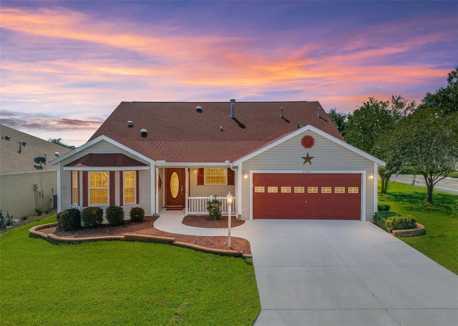 2762 MORVEN PARK WAY, The Villages, FL 32162 Twilight View with Decorative Pavers, Red Gravel and Low-Maintenance Shrubs.