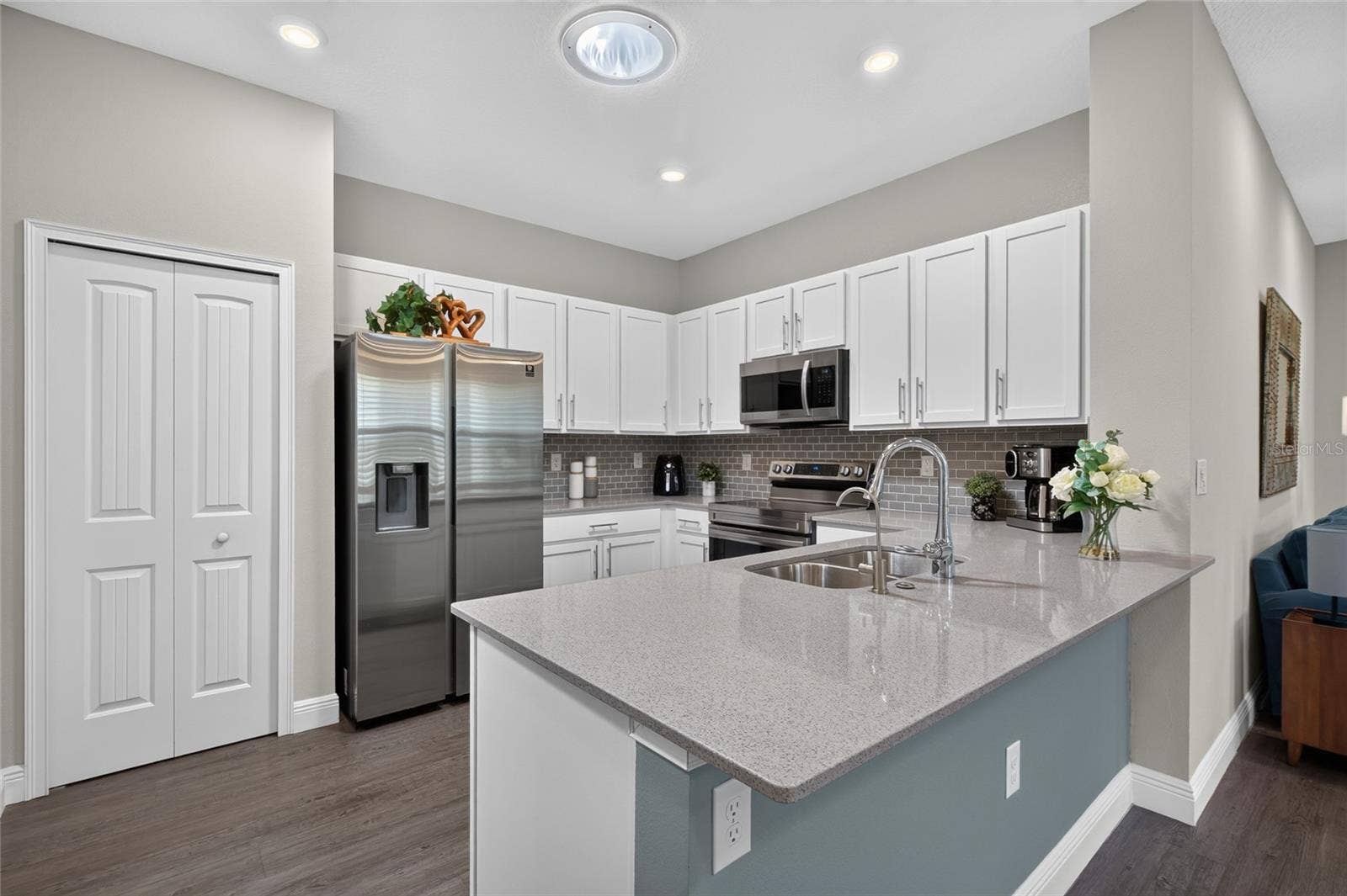 4408 BEDFORD WAY, Leesburg, FL 34748 Kitchen with white shaker cabinets, tile backsplash, stainless steel appliances.