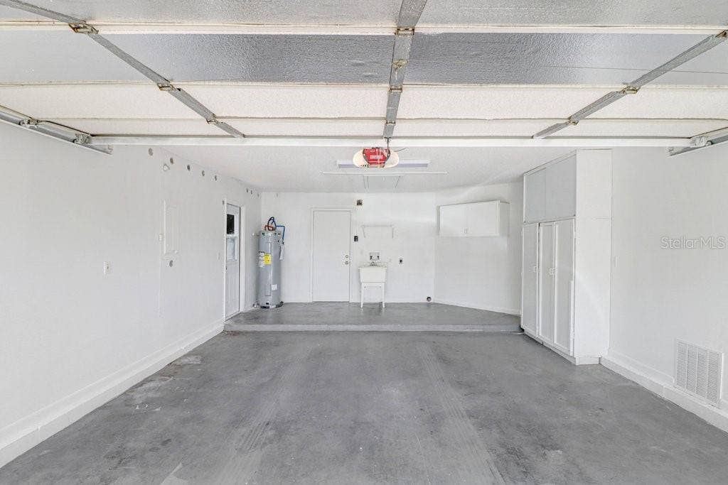 Two car garage with sink and storage cabinets. Side access door to the left.