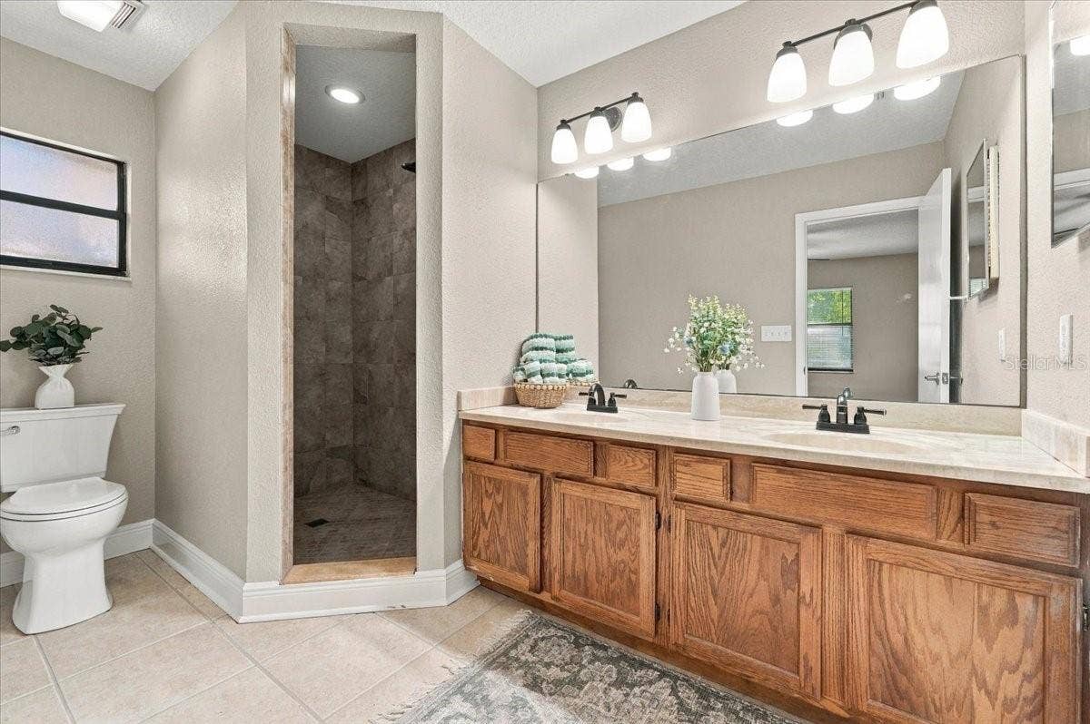 5244 QUIET CREEK LANE, Lakeland, FL 33811 Primary Bath with Dual sinks, walk in shower, new toilet and cermic tile flooring.