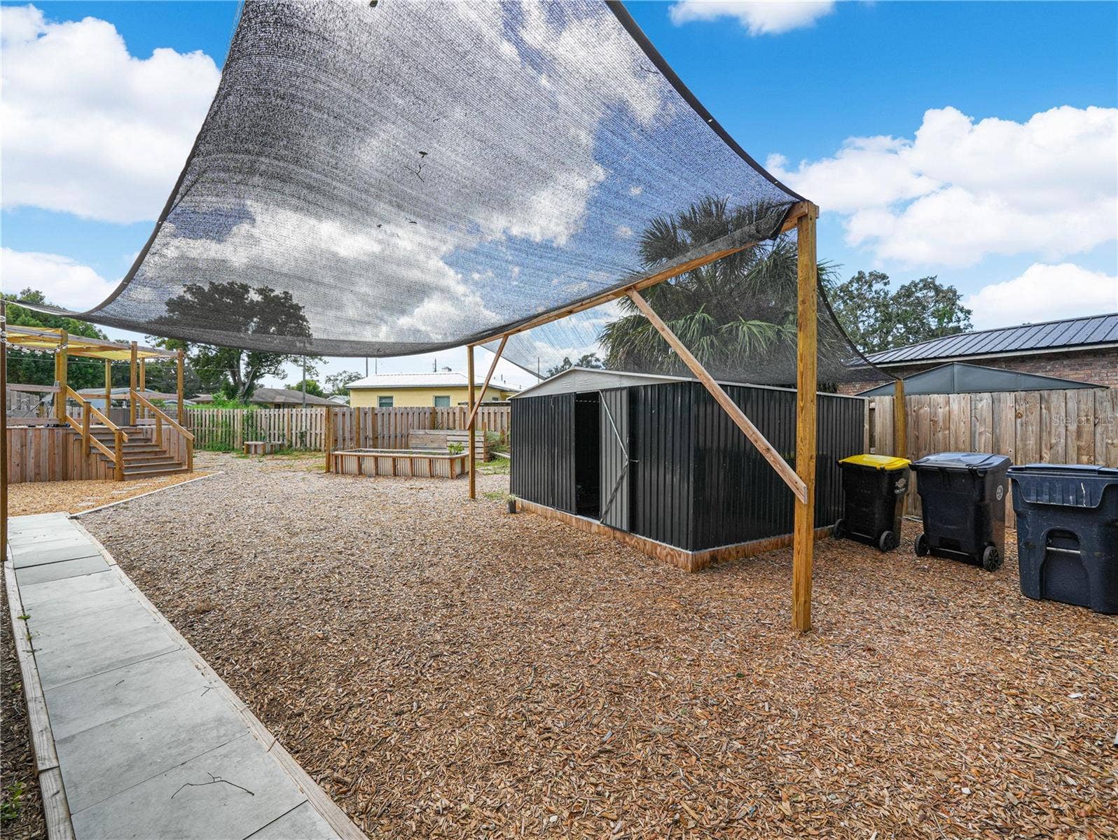 Fully fenced back yard with pool, deck, shed and raised garden beds