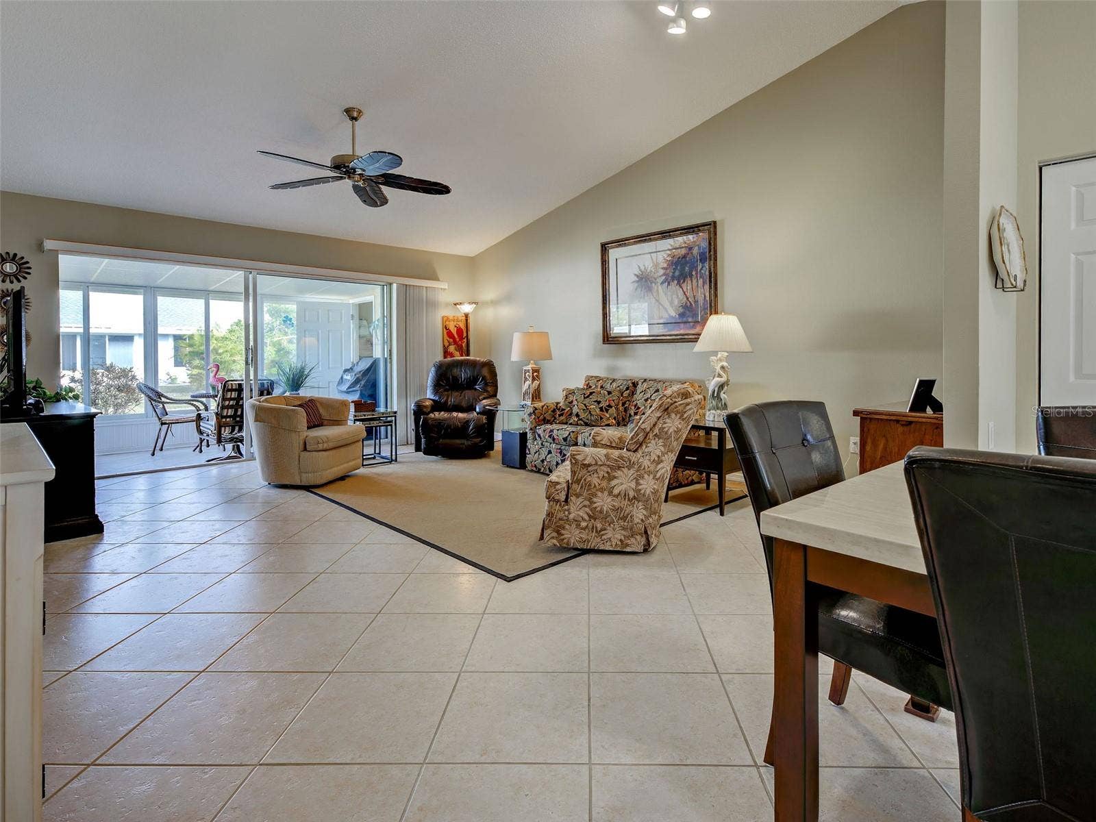 living room with high cathedral ceiling, tile flooring, sliding glass doors to lanai. Open floor plan