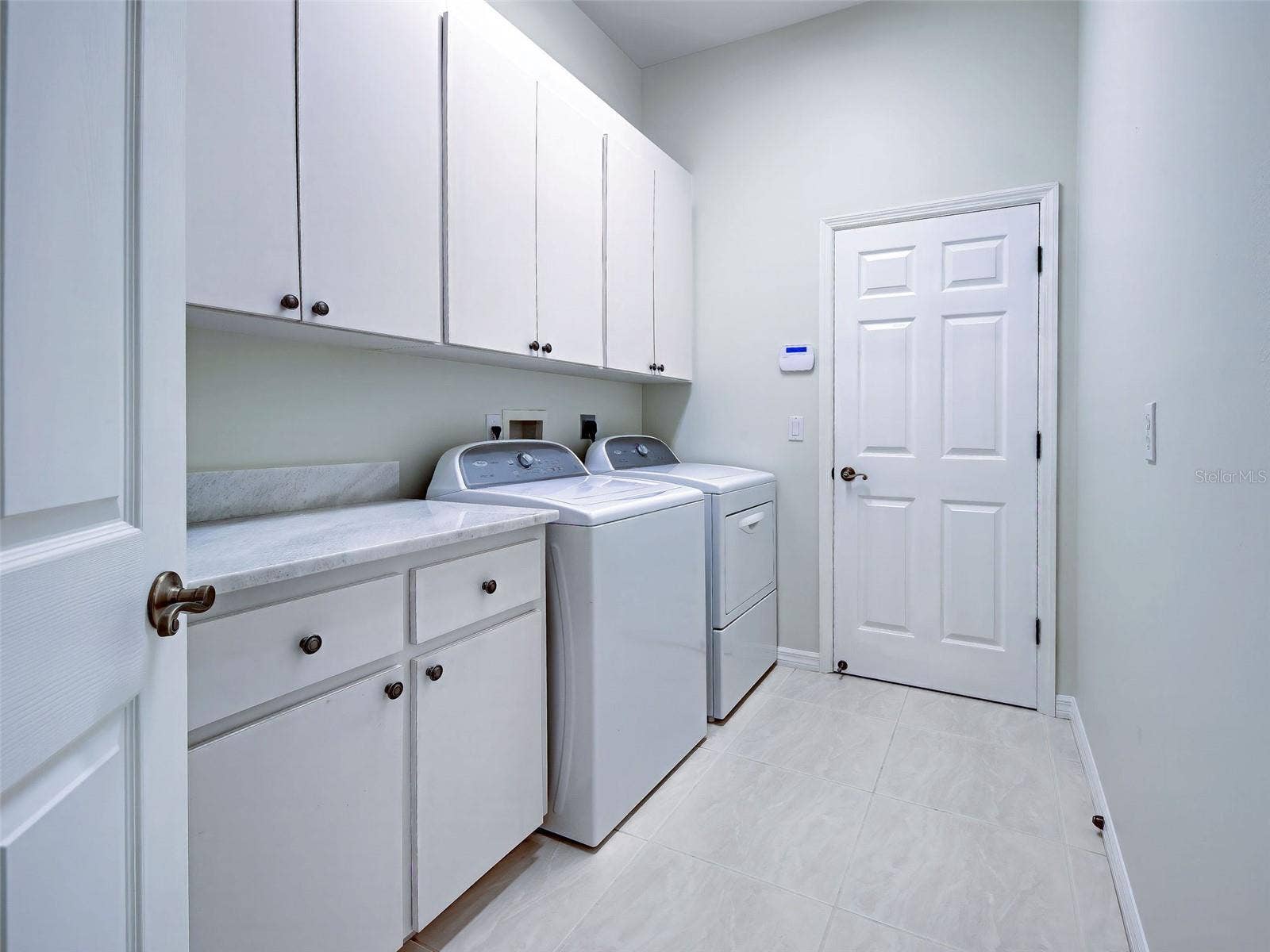 Interior laundry room conveniently leads from the garage to kitchen and has storage and laundry tub