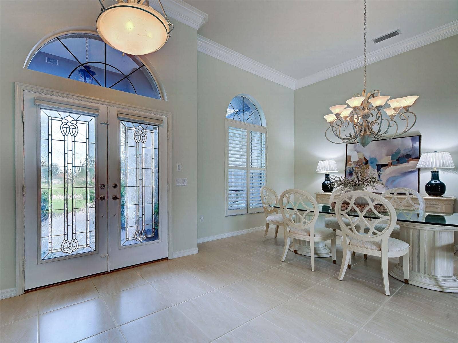 Welcoming foyer with double doors and dining room; so much natural light.