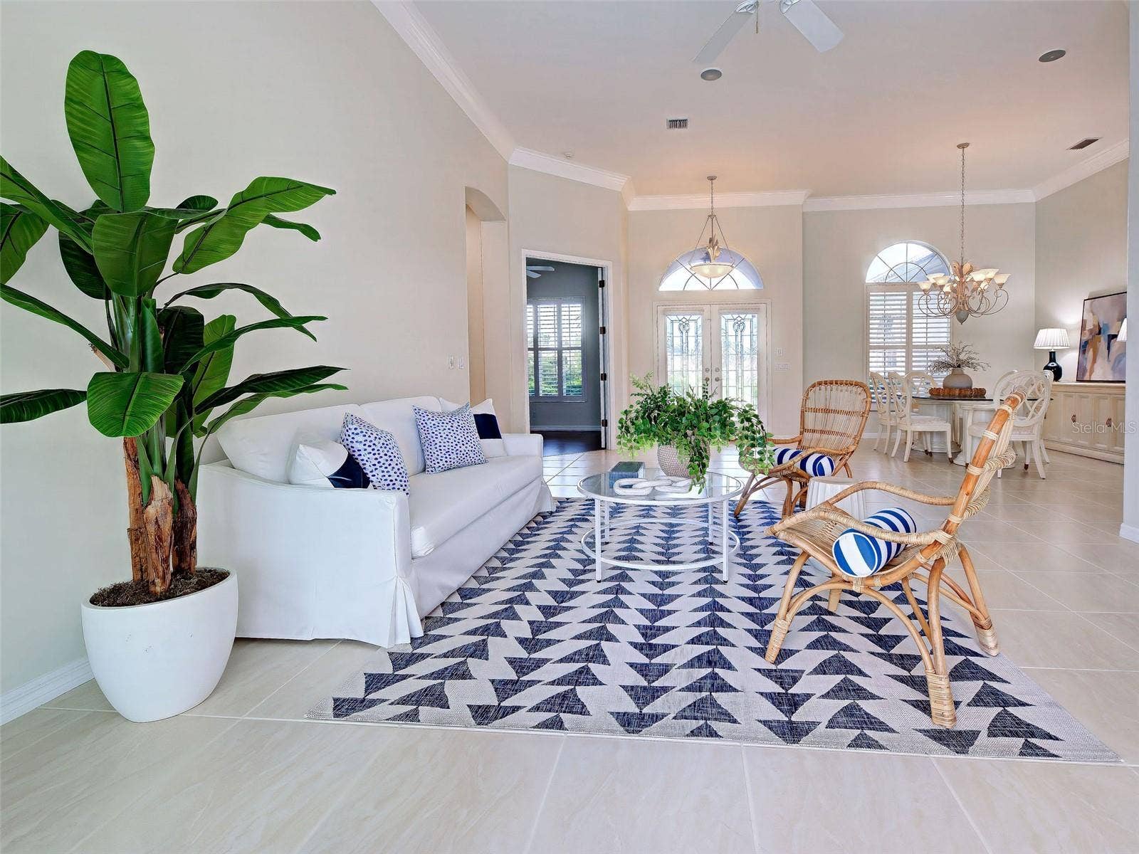 Another view of the great room and dining room.  The over-sized tiles, crown molding, plantation shutters and transom windows make the home so elegant.