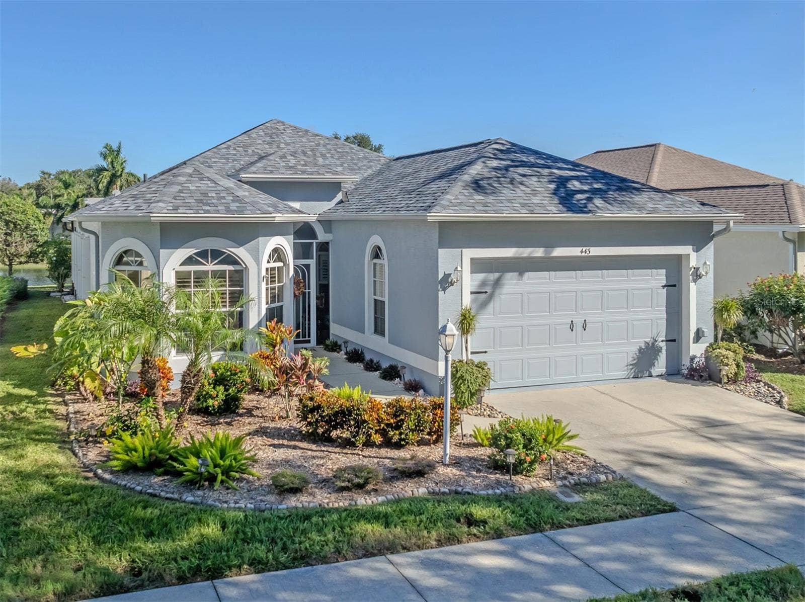 Beautiful curb appeal welcomes you home, featuring a charming bay window, lush mature landscaping, and a lovely glimpse of the peaceful lake beyond!