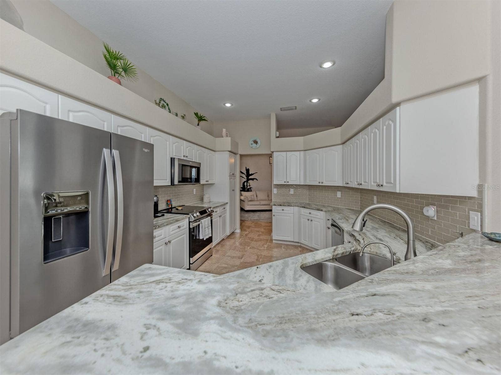 A spacious, beautifully updated kitchen featuring gorgeous granite countertops, crisp white cabinetry, sleek stainless steel appliances, and recessed lighting with dimmer controls to create the perfect ambiance for cooking, gathering, and entertaining!