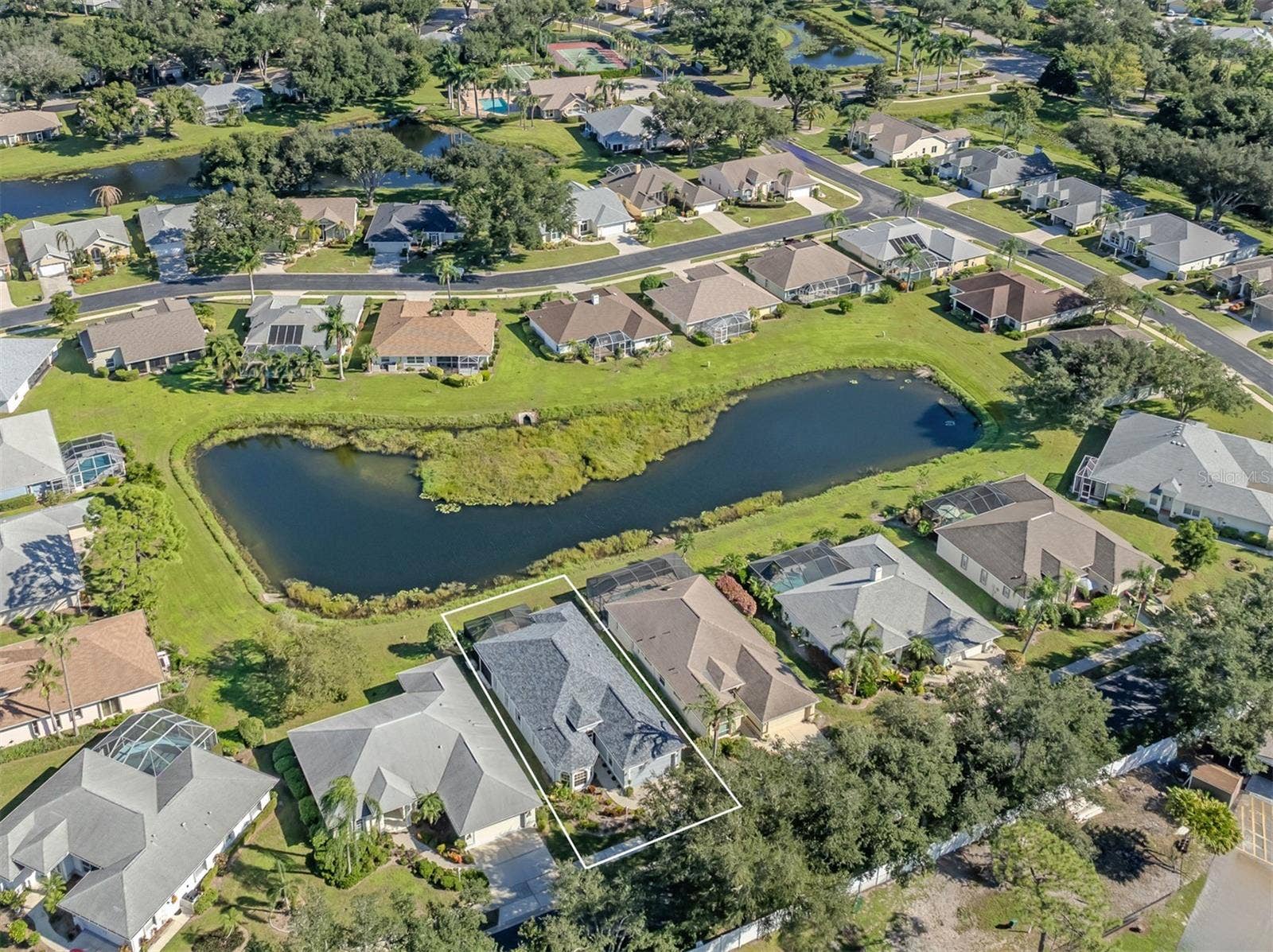 A birds-eye view of this lovely neighborhood, showcasing the home's beautiful setting, sparkling lake, and picturesque surroundings in the Isles of Chestnut Creek!