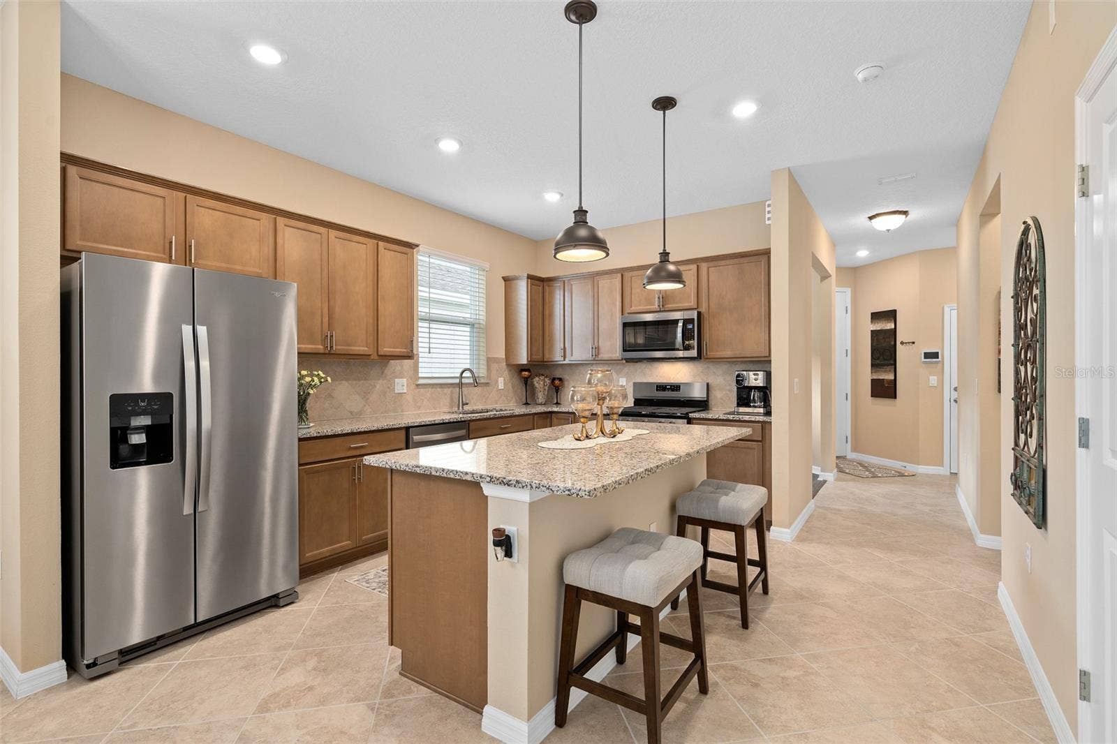 2759 PURPLE MEADOW COURT, Minneola, FL 34715 Enjoy this beautiful open Kitchen with Granite Counters, Solid Wood Cabinetry, Stainless Appliances and Breakfast Bar with Pendant Lighting. The cabinet color in person is a much richer tone than pictured.