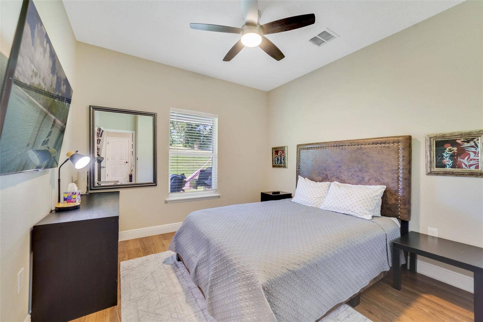 ONE OF THE FIVE BEDROOMScomplete with laminate wood flooringlocated next to a full bathroom on the first floor, provides a perfect space for guests or multigenerational living. Bedroom 5.