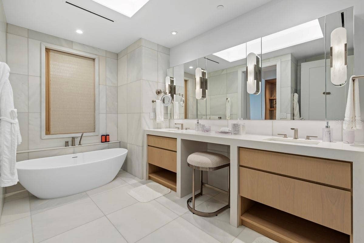 10160 AUTUMN MIST LANE, #402, Orlando, FL 32836 Luxurious primary bath featuring custom vanities, marble floors, walls and shower and lavish freestanding soaking tub.