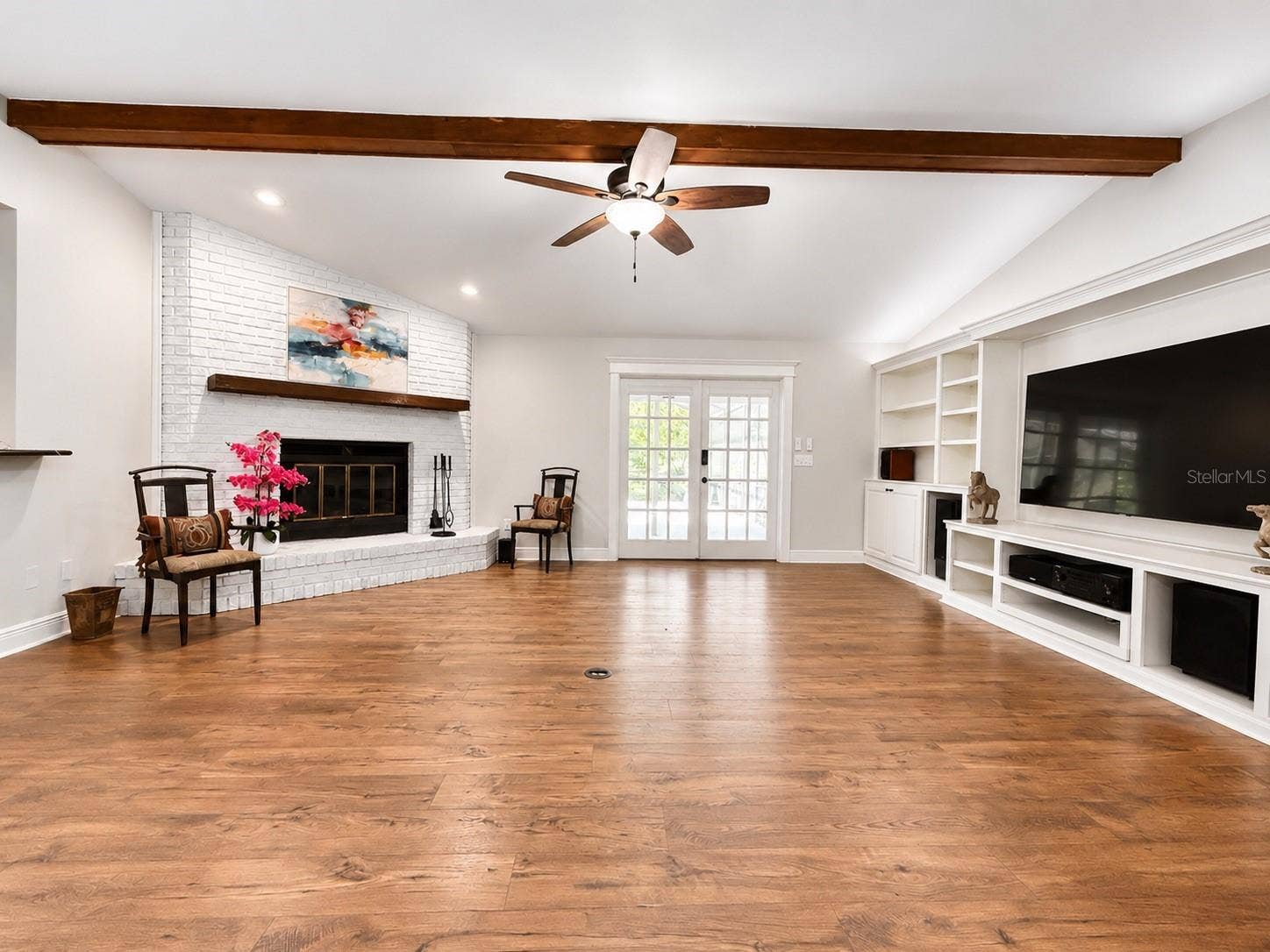 14140 COUNTRY ESTATE DRIVE, Winter Garden, FL 34787 A warm and elegant living space designed to impress, featuring soaring ceilings, rich luxury flooring, exposed beam, a charming white brick fireplace, an beautiful natural light. This room offers the perfect blend of comfort, character, and elevated style.