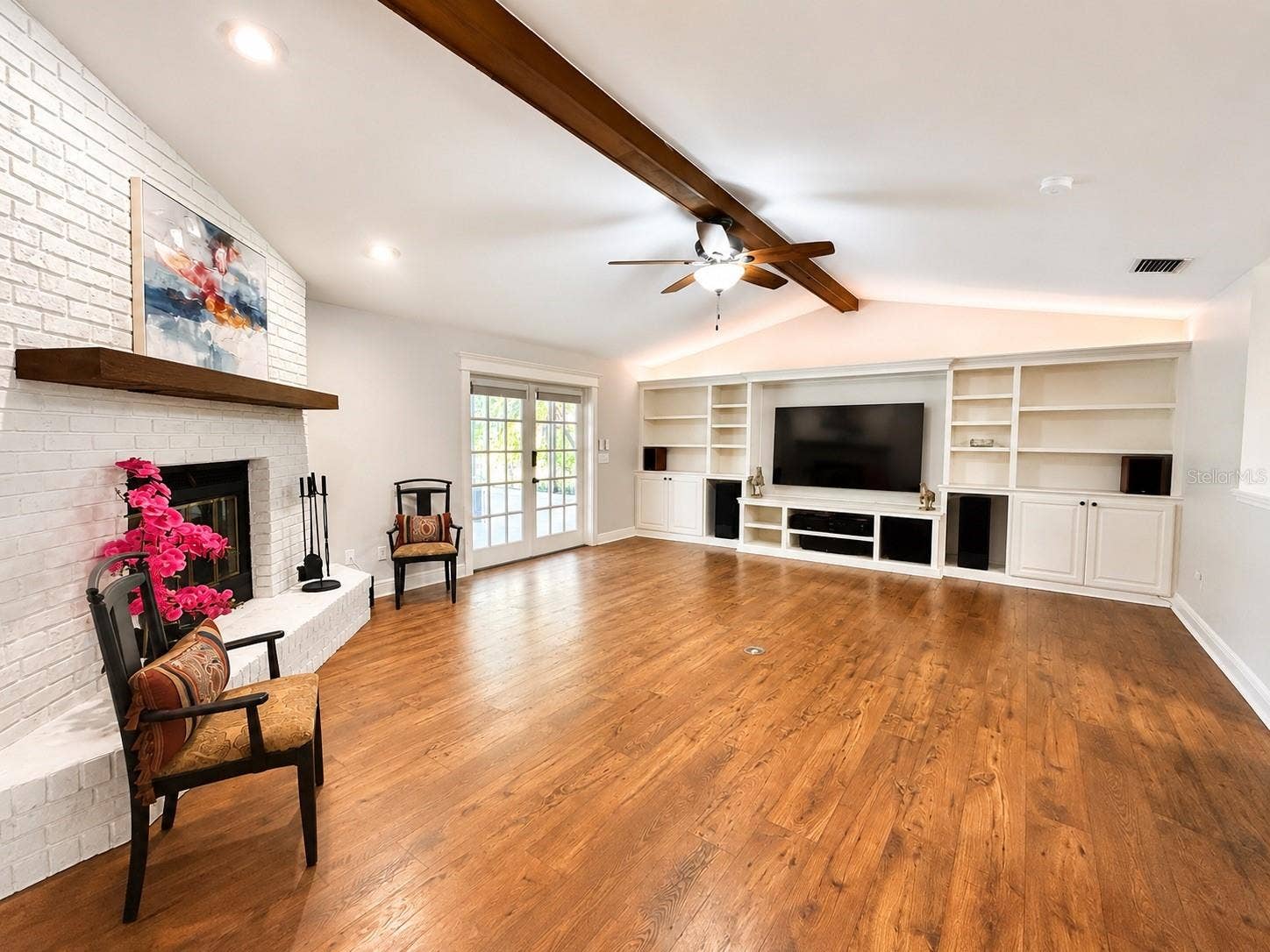 14140 COUNTRY ESTATE DRIVE, Winter Garden, FL 34787 A stylish living room made to glow, with a cozy white brick fireplace, and a custom entertainment wall featuring color-changing lights for the perfect movie-night mood.