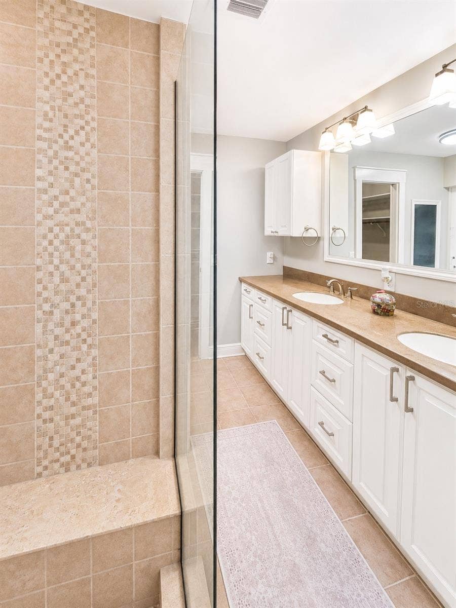 14140 COUNTRY ESTATE DRIVE, Winter Garden, FL 34787 Private primary bath with a spacious tiled shower, custom built-in bench, long dual vanity, and a clean spa-like feel.