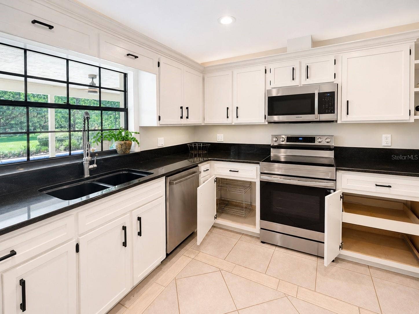 14140 COUNTRY ESTATE DRIVE, Winter Garden, FL 34787 Bright, stylish kitchen with crisp cabinetry, sleep black counters, custom pull outs, and a brand new stove. The pass through window opens right to the pool and patio, making entertaining effortless.
