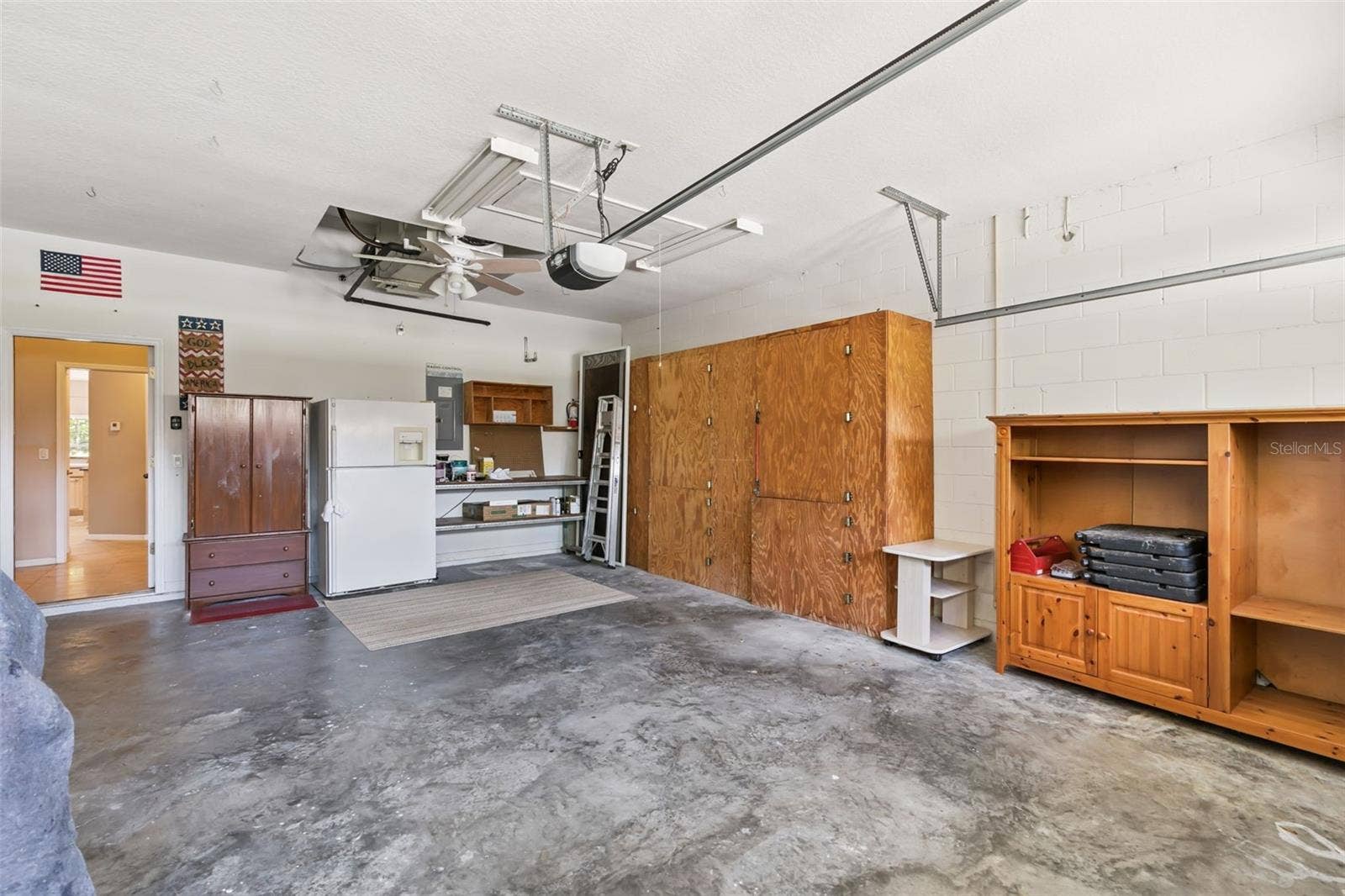 237 STRATHMORE CIRCLE, Kissimmee, FL 34744 Oversized garage with built-in shelves and pull-down ladder system for attic access and additional storage.