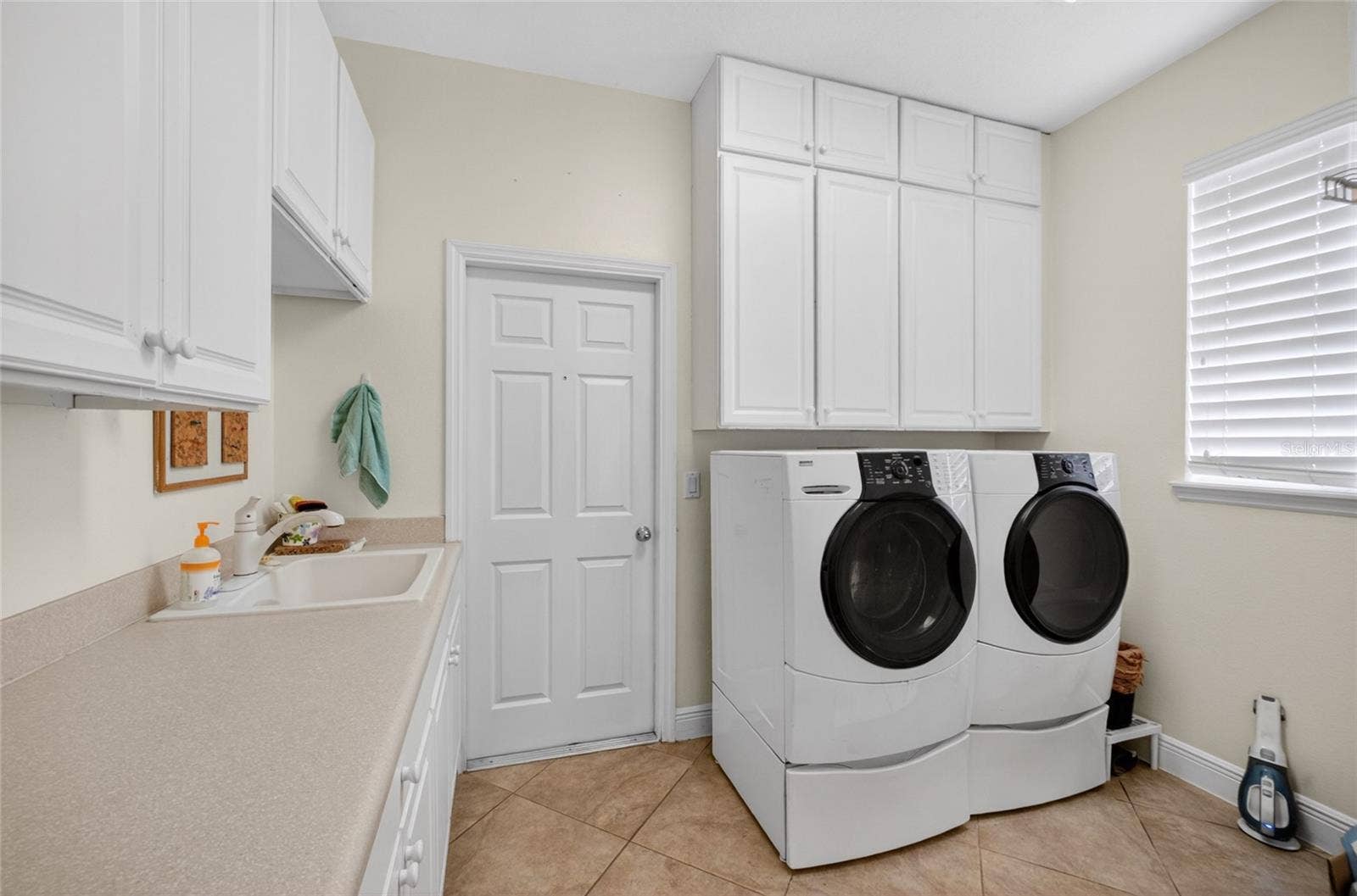 279 ZACHARY WADE STREET, Winter Garden, FL 34787 First flr laundry room. Washer and dryer remain. Built in white cabinets for storage.