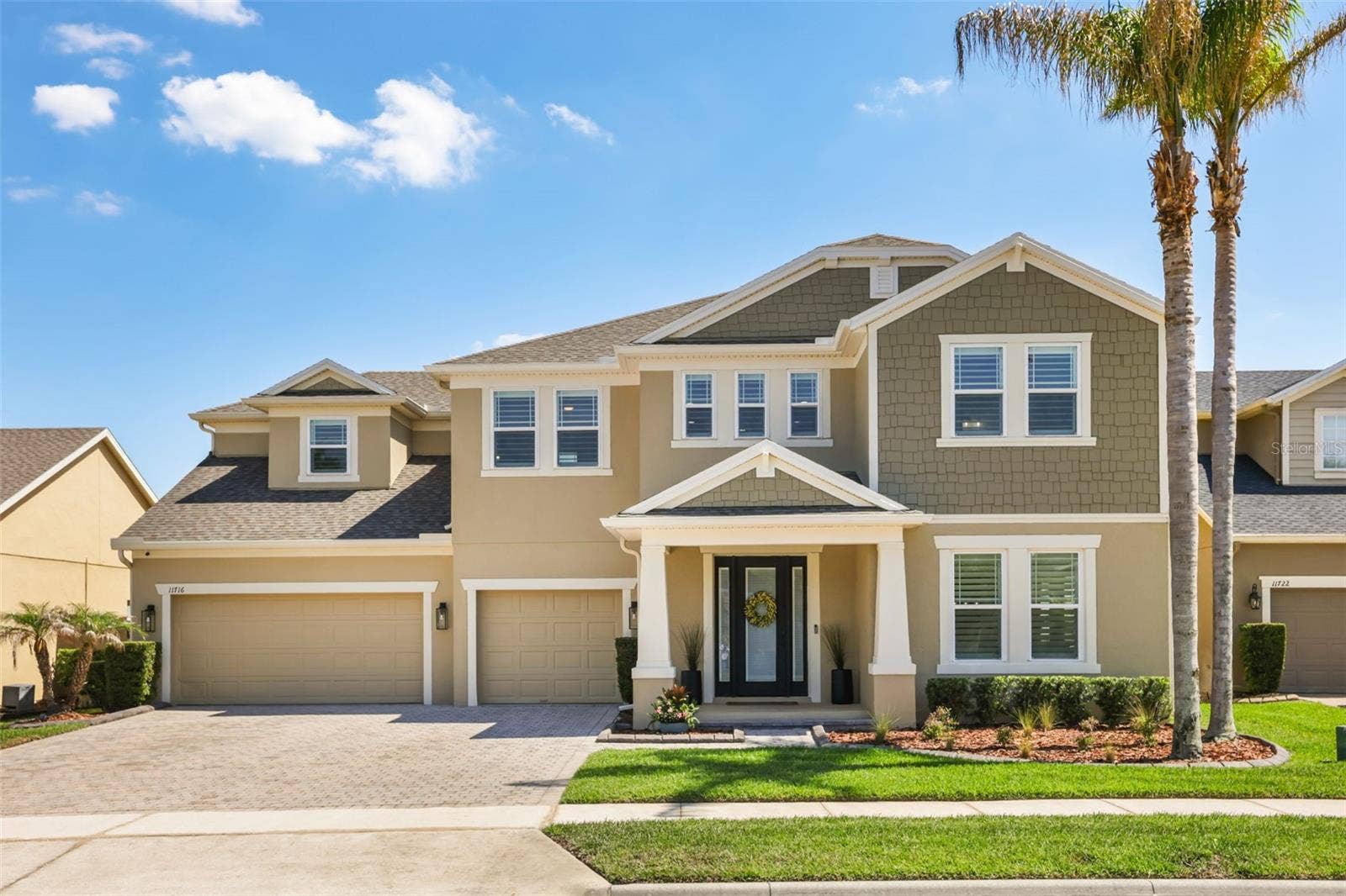 11716 SHELTERING PINE DRIVE, Orlando, FL 32836 A polished two-story exterior with a paver driveway, three-car garage, covered entry, and manicured landscaping framed by mature palms.