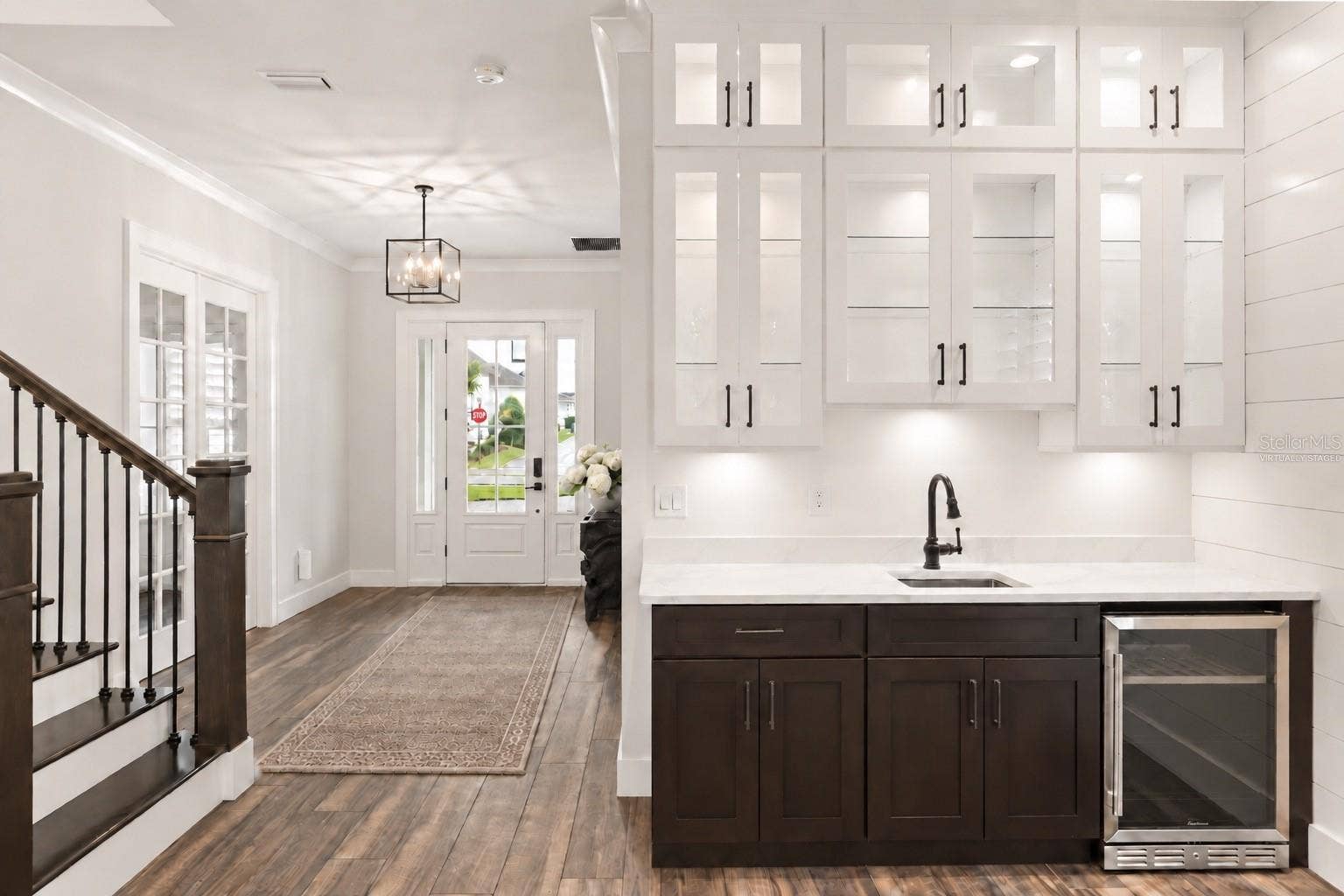 907 CELADON STREET, Winter Garden, FL 34787 BUILT-IN WET BARA built-in wet bar with sink, beverage refrigerator and glass-front cabinetry sits just off the foyer, opening to the main living area for easy entertaining.Virtually staged, added runner and floral in foyer.