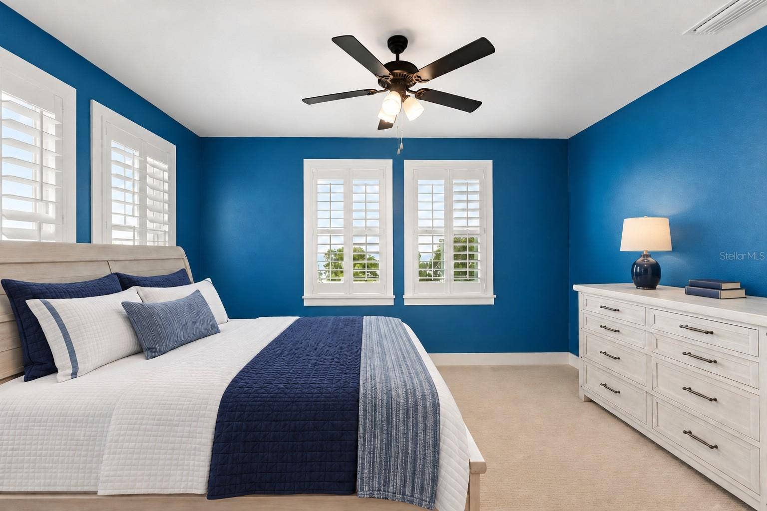 907 CELADON STREET, Winter Garden, FL 34787 4TH BEDROOM/JACK&JILL. Lots of windows for great natural light. Back side of property. Virtual staging: items on floor removed, wall photos, accent rug, items on dresser. Lamp and bedding added