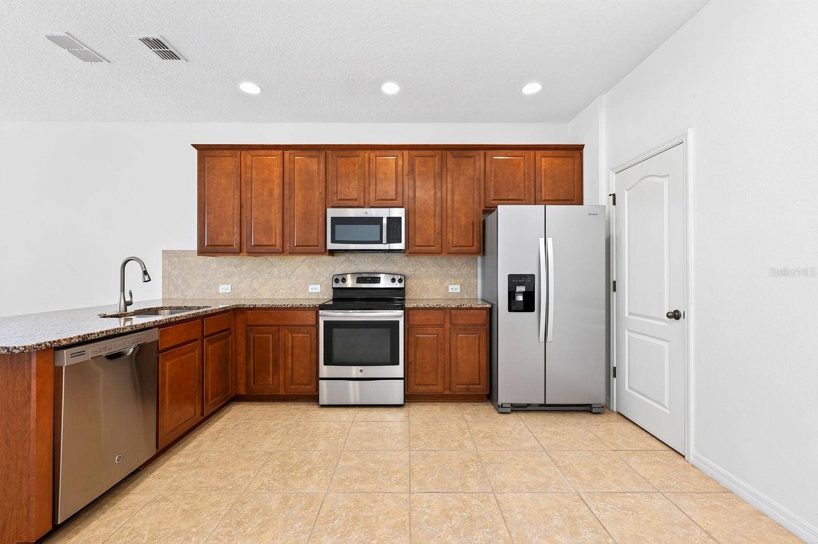 11429 BROWNSTONE STREET, Windermere, FL 34786 The kitchen is designed to be both functional and inviting, featuring rich cabinetry, granite countertops, a tiled backsplash, STAINLESS STEEL APPLIANCES, pantry storage, and a breakfast bar that overlooks the living and dining areas.