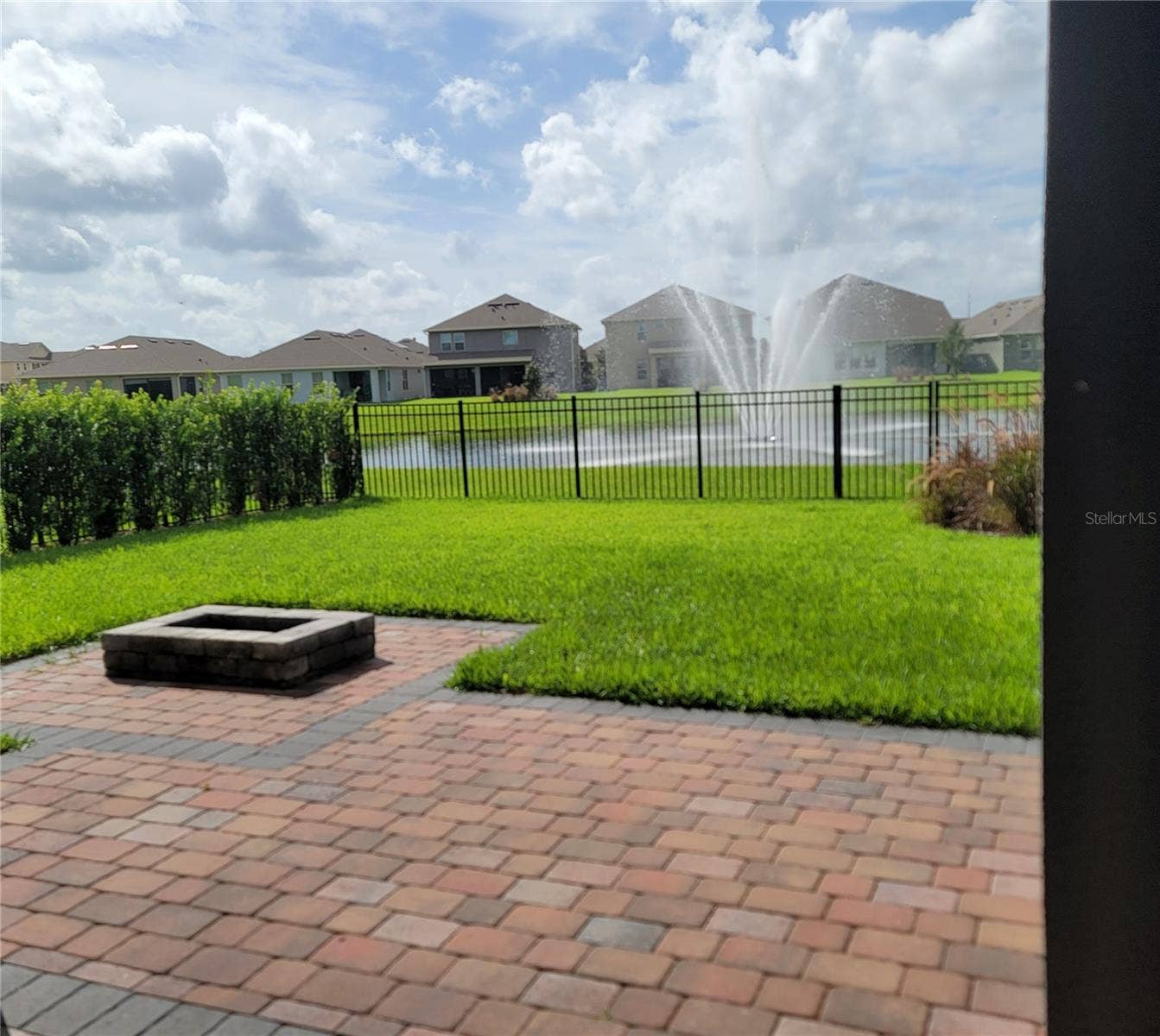 16124 AZURE KEY STREET, Winter Garden, FL 34787 Private Fenced Yard with extended pavers, firepit, privacy bushes, and water view overlooking beautiful fountain