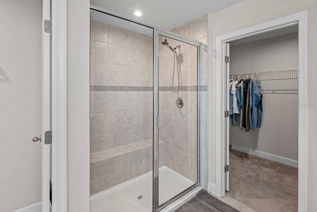 Shower with floor to ceiling tile work and Primary walk-in closet 2
