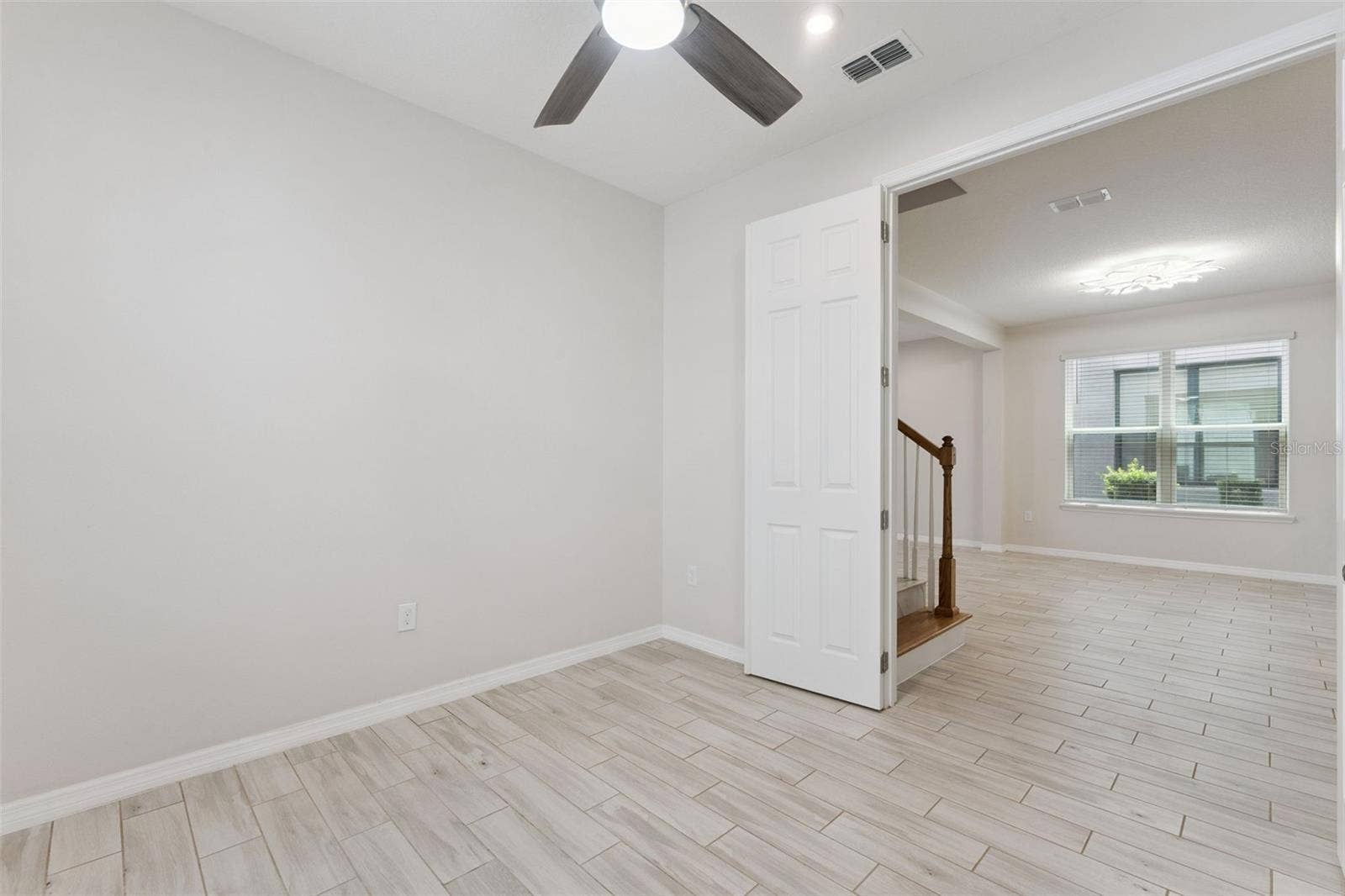 Downstairs Study  Bright, versatile main-level study with neutral finishes, tile flooring, a ceiling fan, and natural light, offering flexible space for a home office, reading room, or creative workspace.